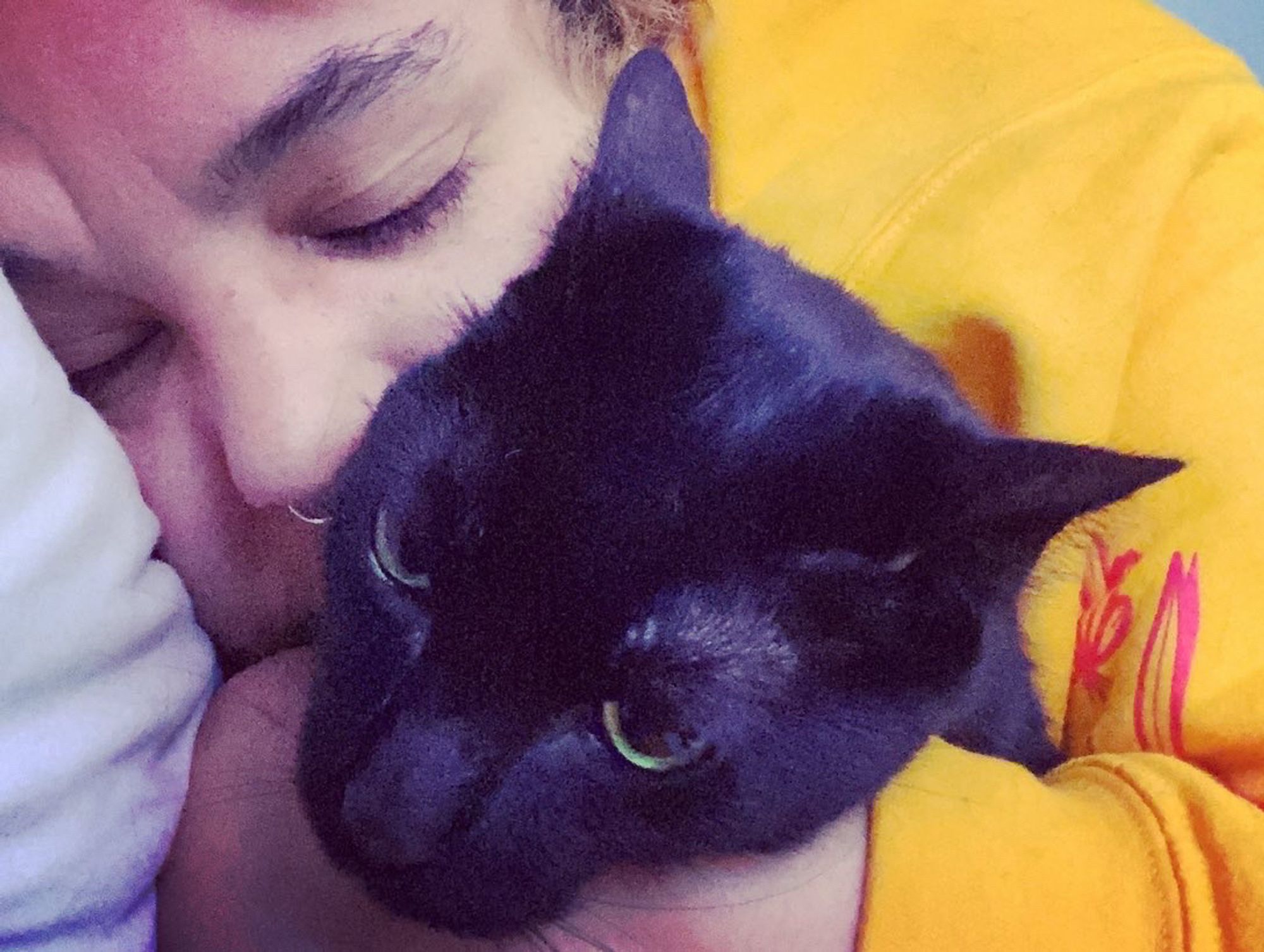 Me hugging my black cat, I’m in a yellow sweatshirt.