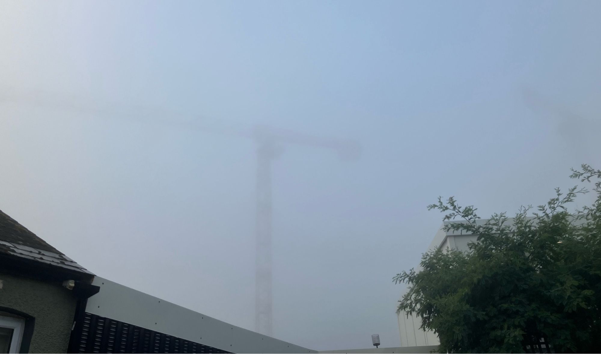 Photo of building crane half hidden in the fog