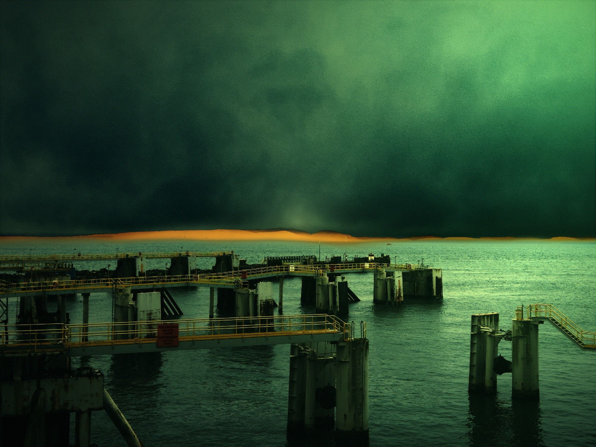 An eerie green oceanscape with distant mountains