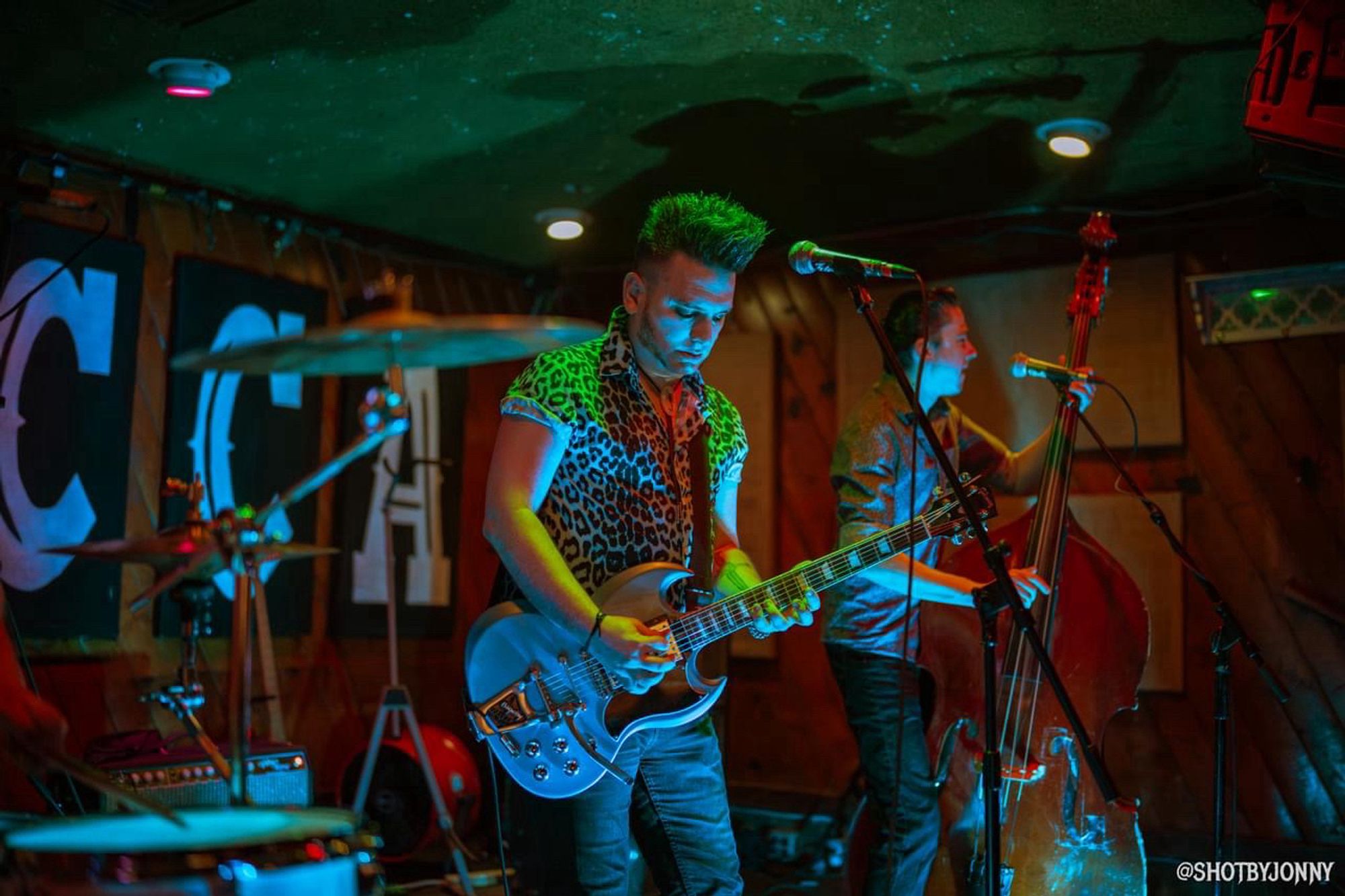 Singer / guitarist Nick Feratu on stage with a blue Gibson SG guitar, shrouded in blue and green light.