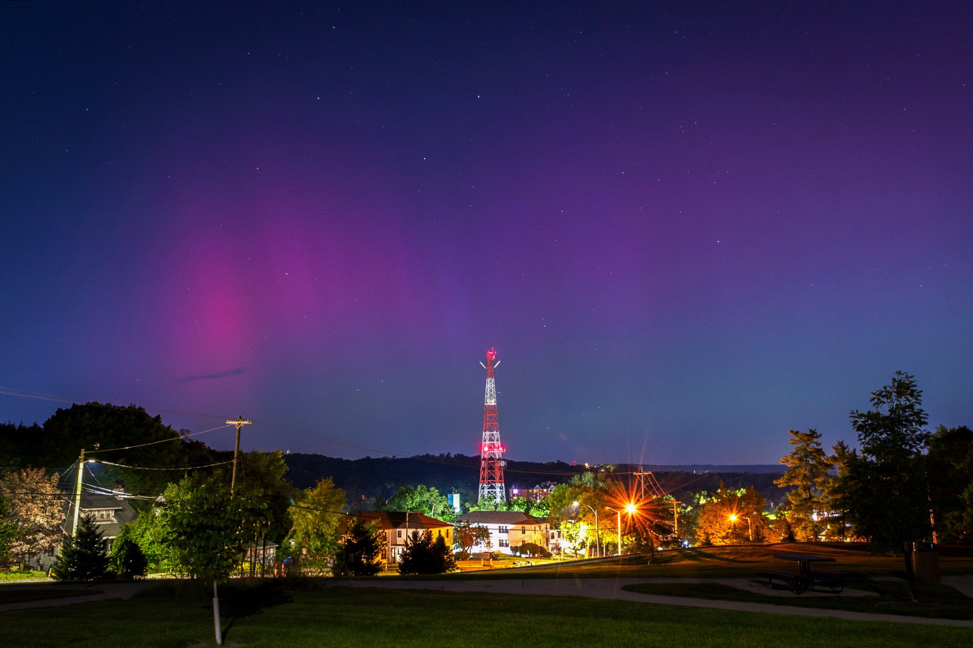 A night photograph: an area of magenta hue hovers over a cityscape, television tower in the middle of the frame. The image was made in Kalamazoo, Michigan.