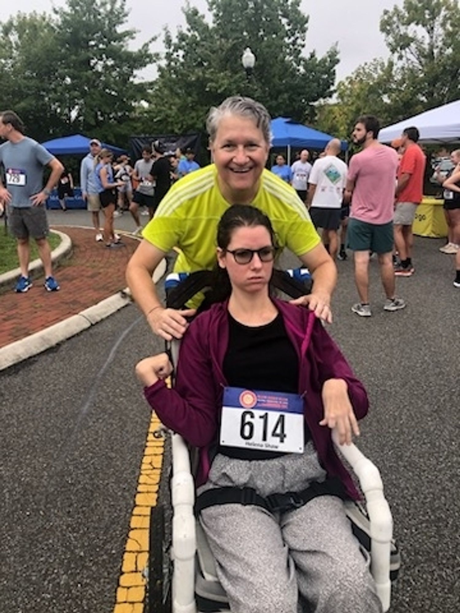 Young woman in wheelchair with her father smiling behind her