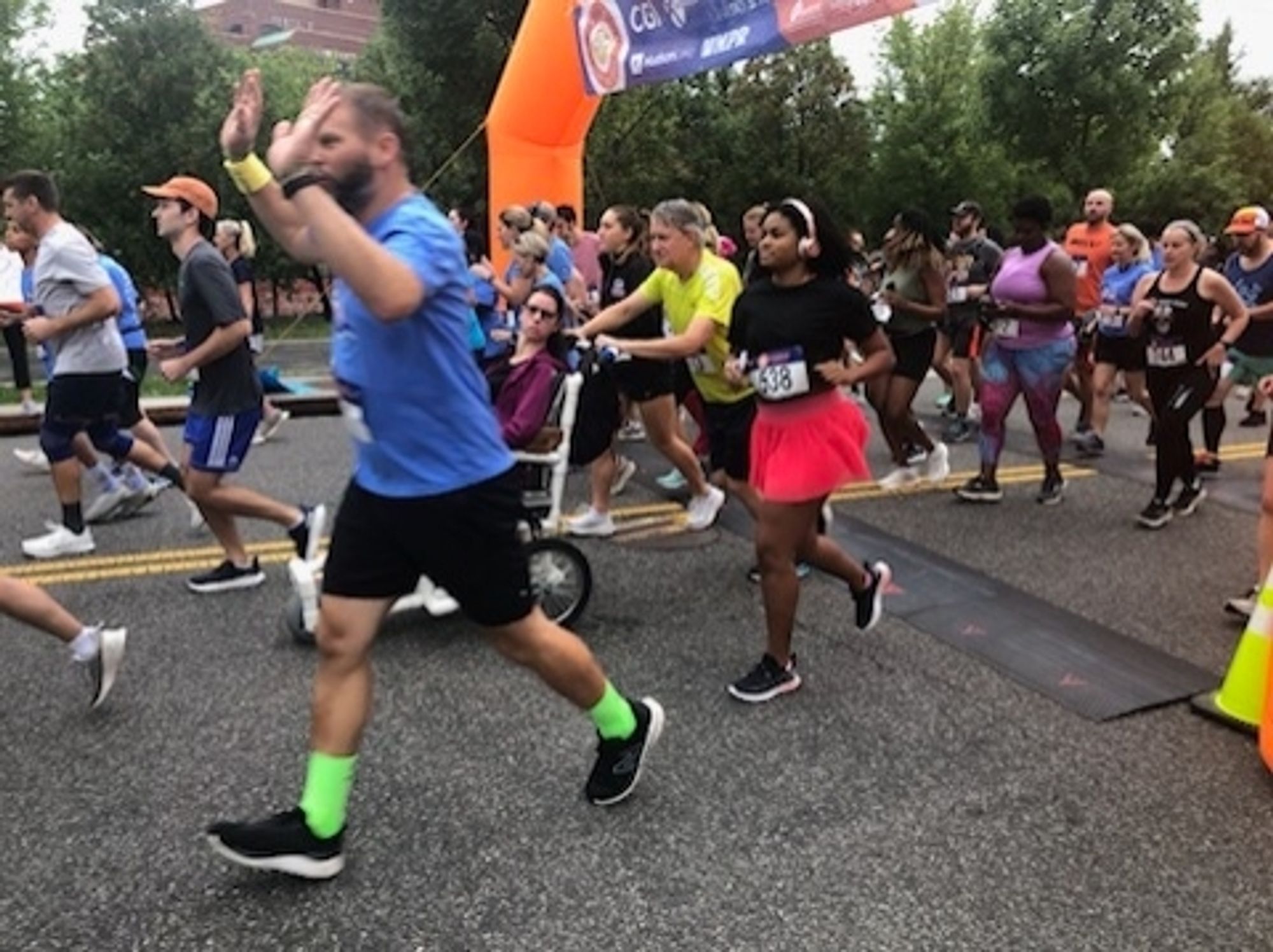 Young woman in wheelchair pushed by her father start a running race