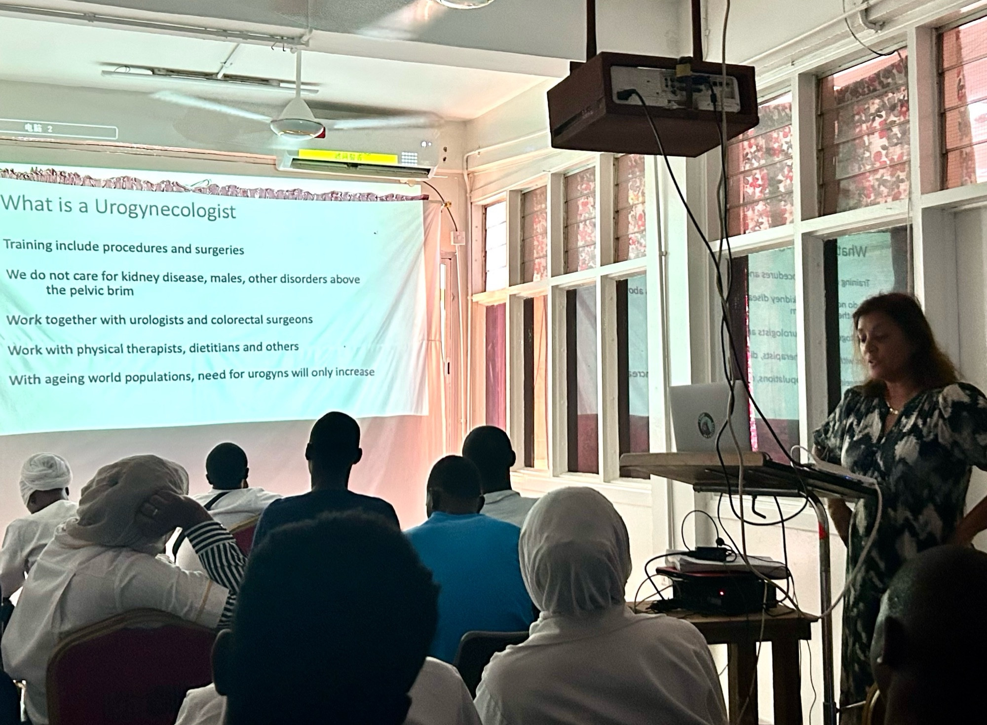 A physician lecturing to a group of medical students, med officers, learners and residents about the field of gynecology