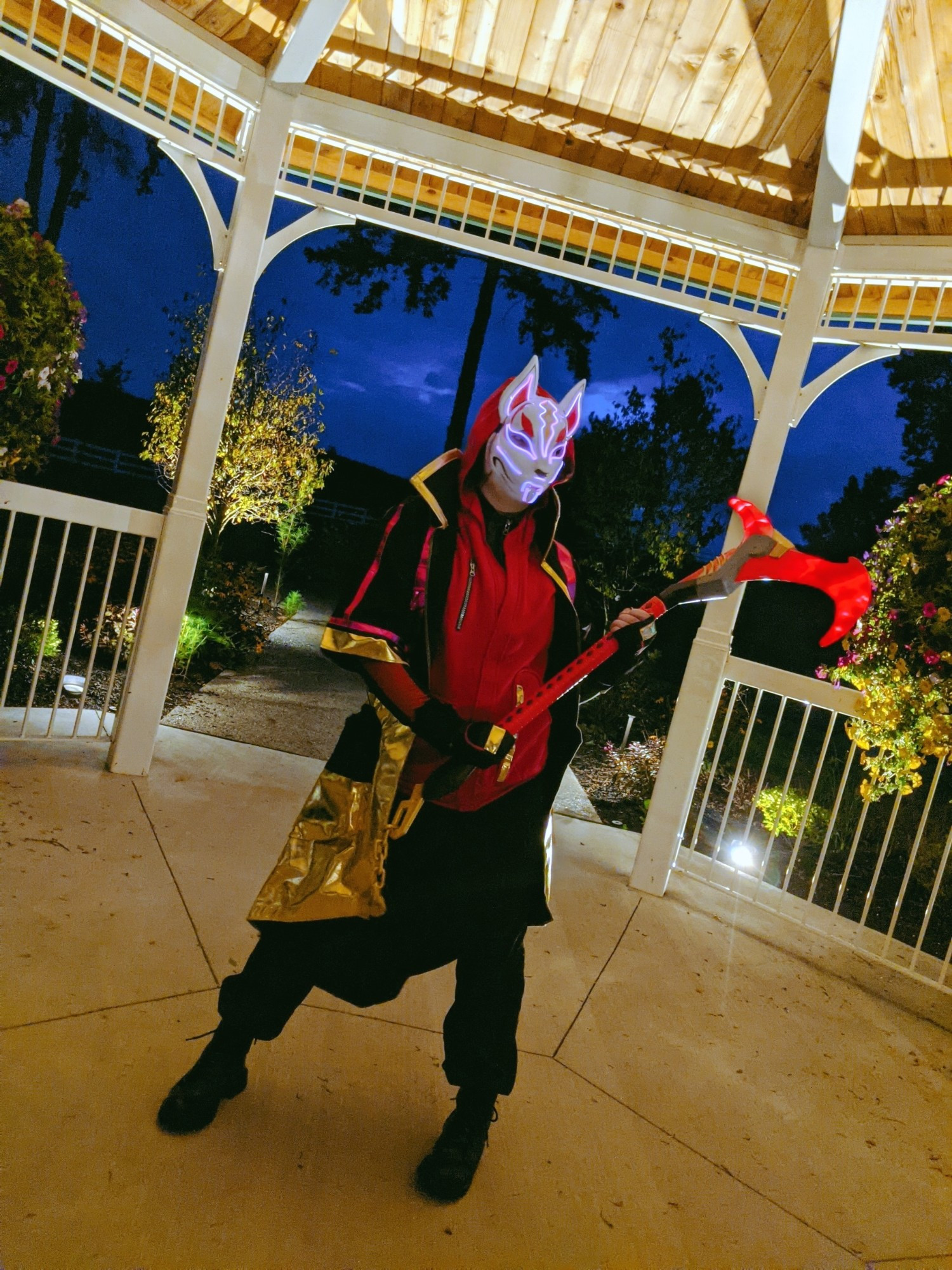 At night, Linds stands inside of a gazebo, dressed as Drift from Fortnite and holding his Rift Edge. An ominous sky looks above.