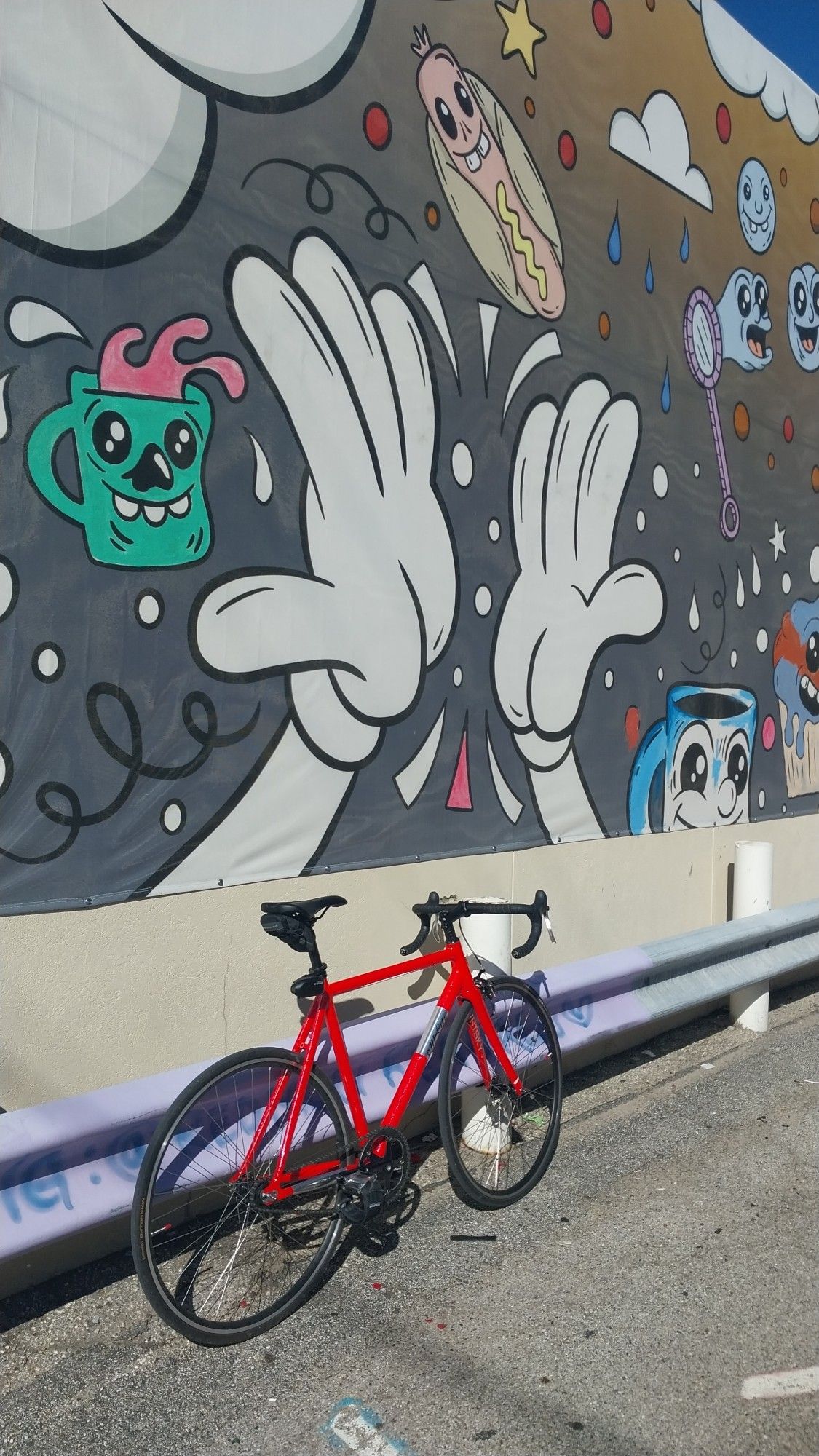 Pink All City Thunderdome Bicycle in front of a mural featuring multiple figures in the "rubberhose / cuphead" style.