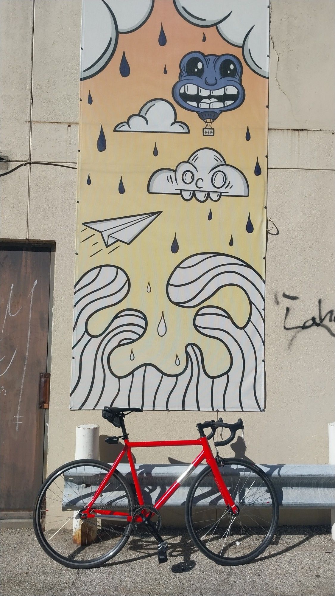 Pink All City Thunderdome Bicycle in front of a small, vertical mural some clouds, waves a random face and a paper airplane in the "rubberhose / cuphead" style.