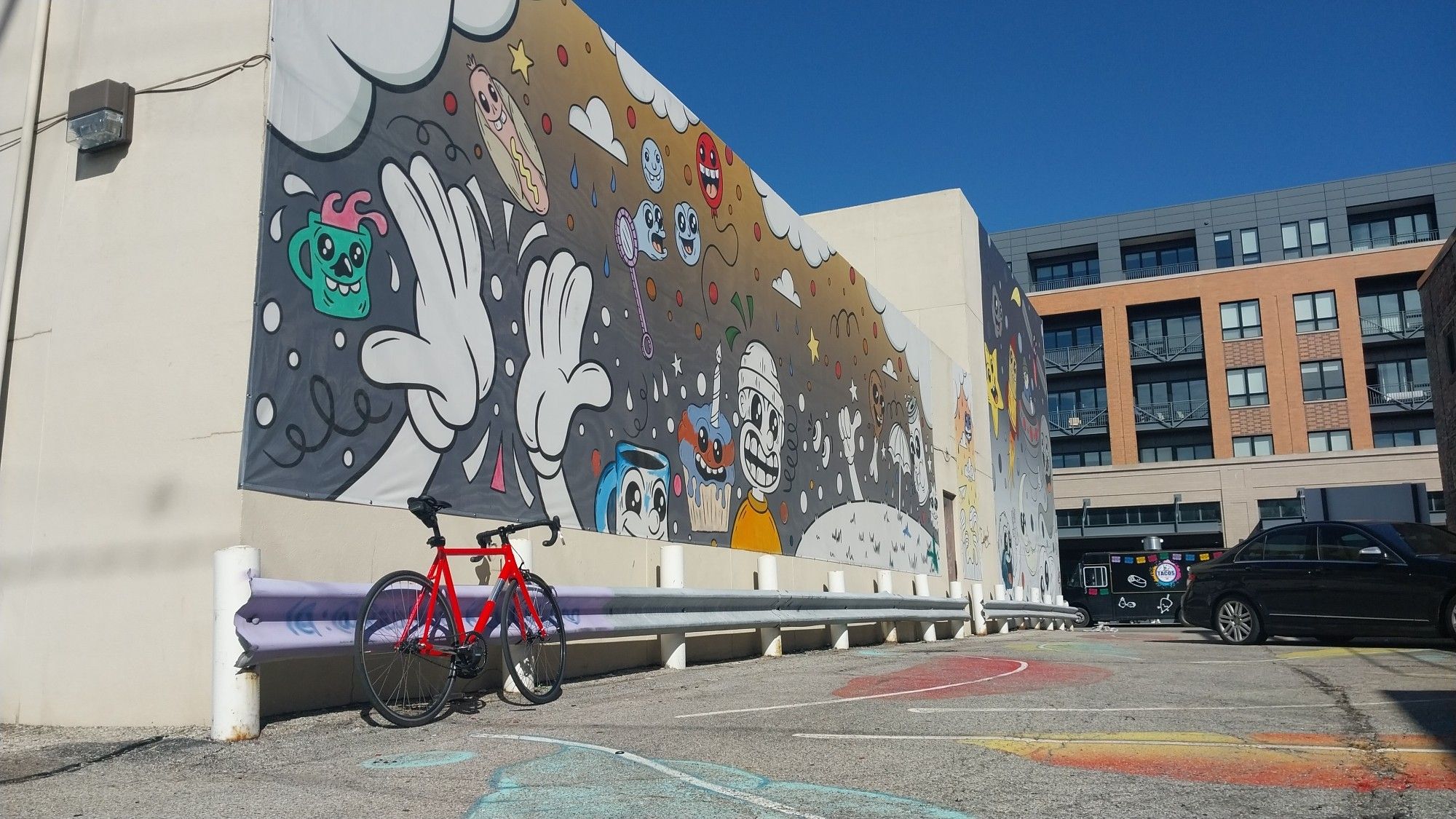 Pink All City Thunderdome Bicycle in front of a mural featuring multiple figures in the "rubberhose / cuphead" style.