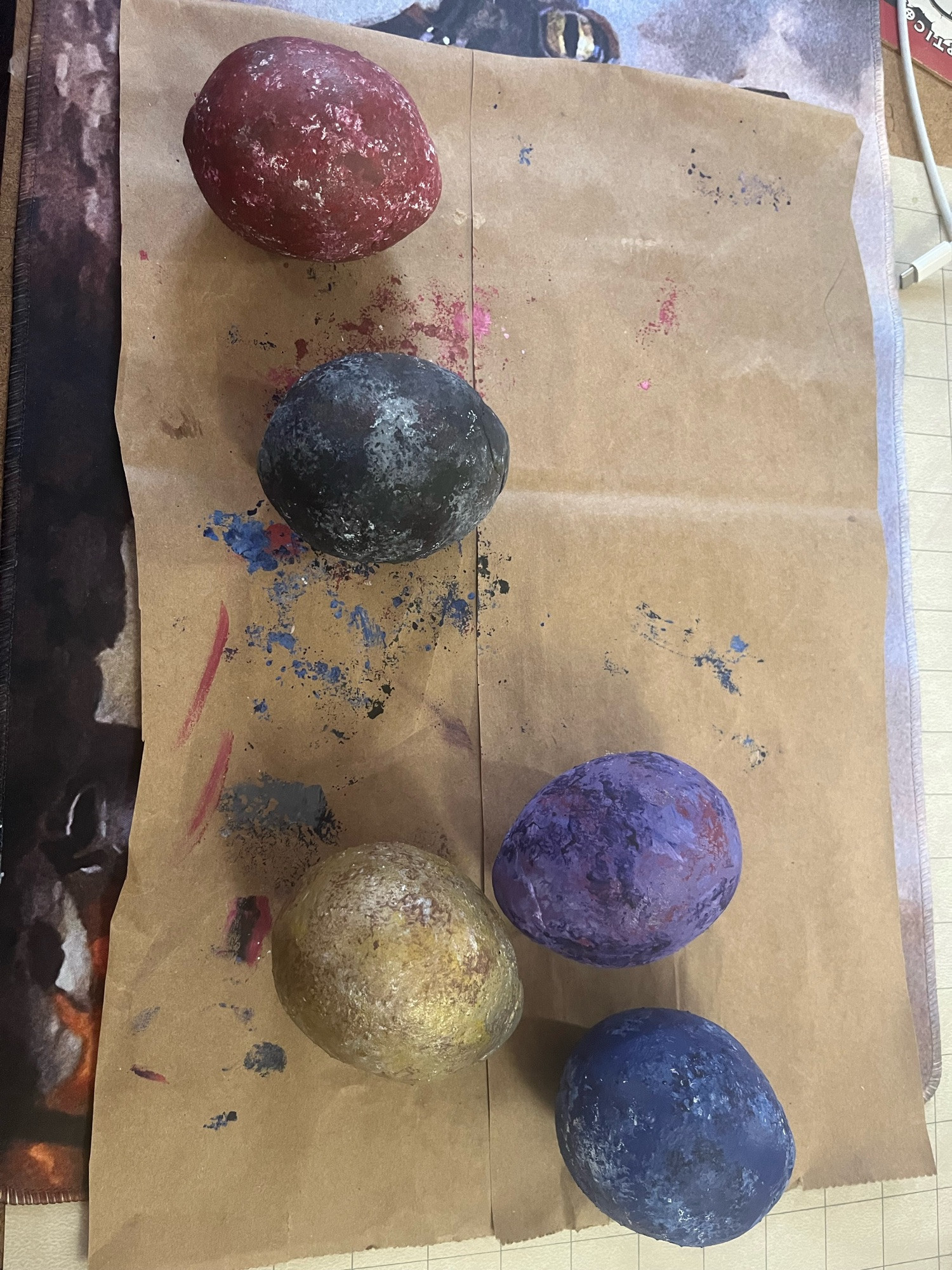 Red, black, gold,purple, and blue dragon eggs on a brown paper bag