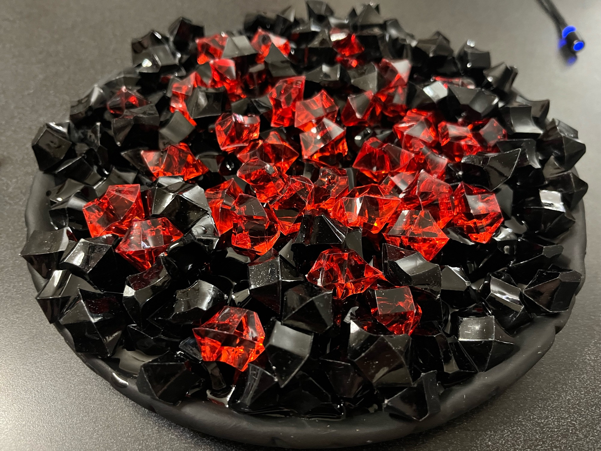 Black and red plastic crushed rocks on a black clay base