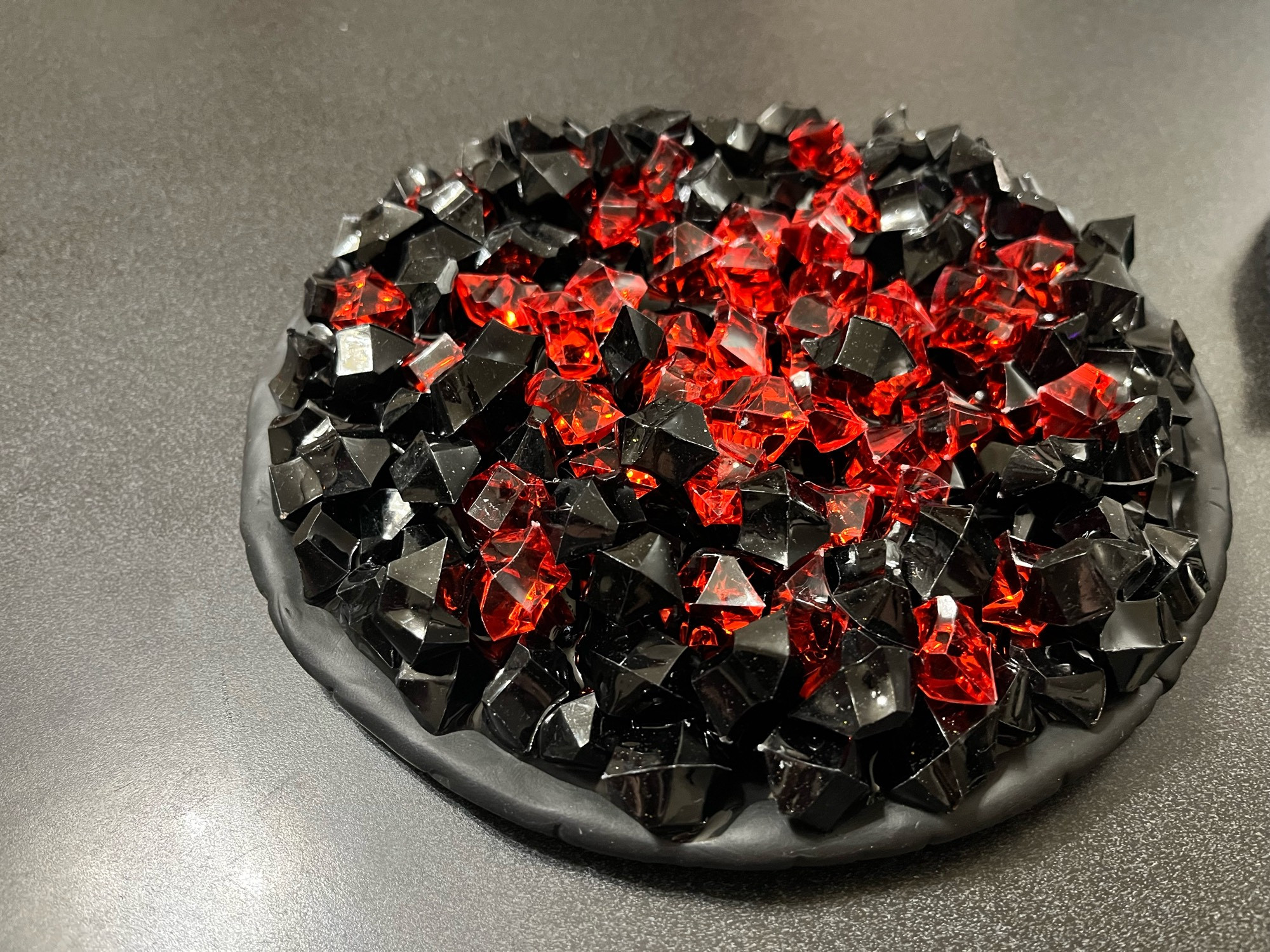 Black and red plastic crushed rocks on a black clay base