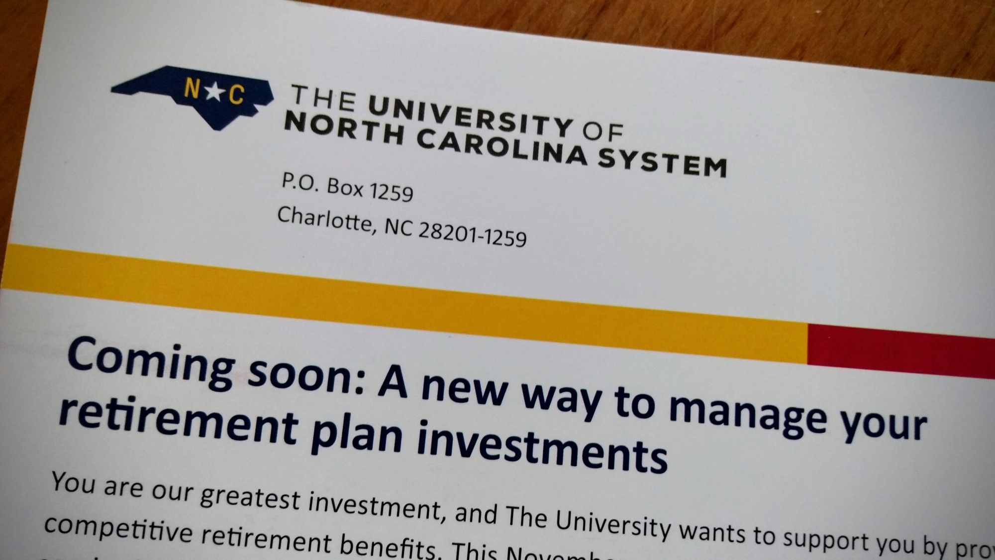 Mailer from the University of North Carolina system (but addressed at a PO box down in Charlotte) proclaiming "Coming soon: A new way to manage your retirement plan investments." The paragraph copy in the shot reads, "You are our greatest investment, and The University want to support you by pro (…) competitive retirement benefits. This November (…)"