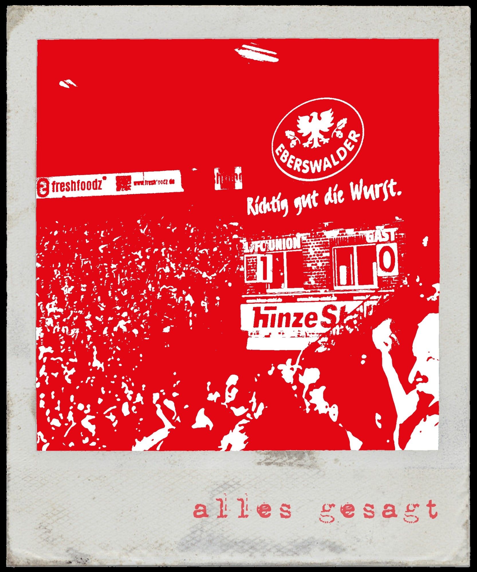 In eine Alte Anzeigetafel wir eine Eins händisch hineingeschoben. Die Anzeigetafel seht im Stadion an der Alten Försterei und es stehen viele Zuschauer links und rechts daneben. Das Bild ist in Rot Weiß und Polaroid Format.