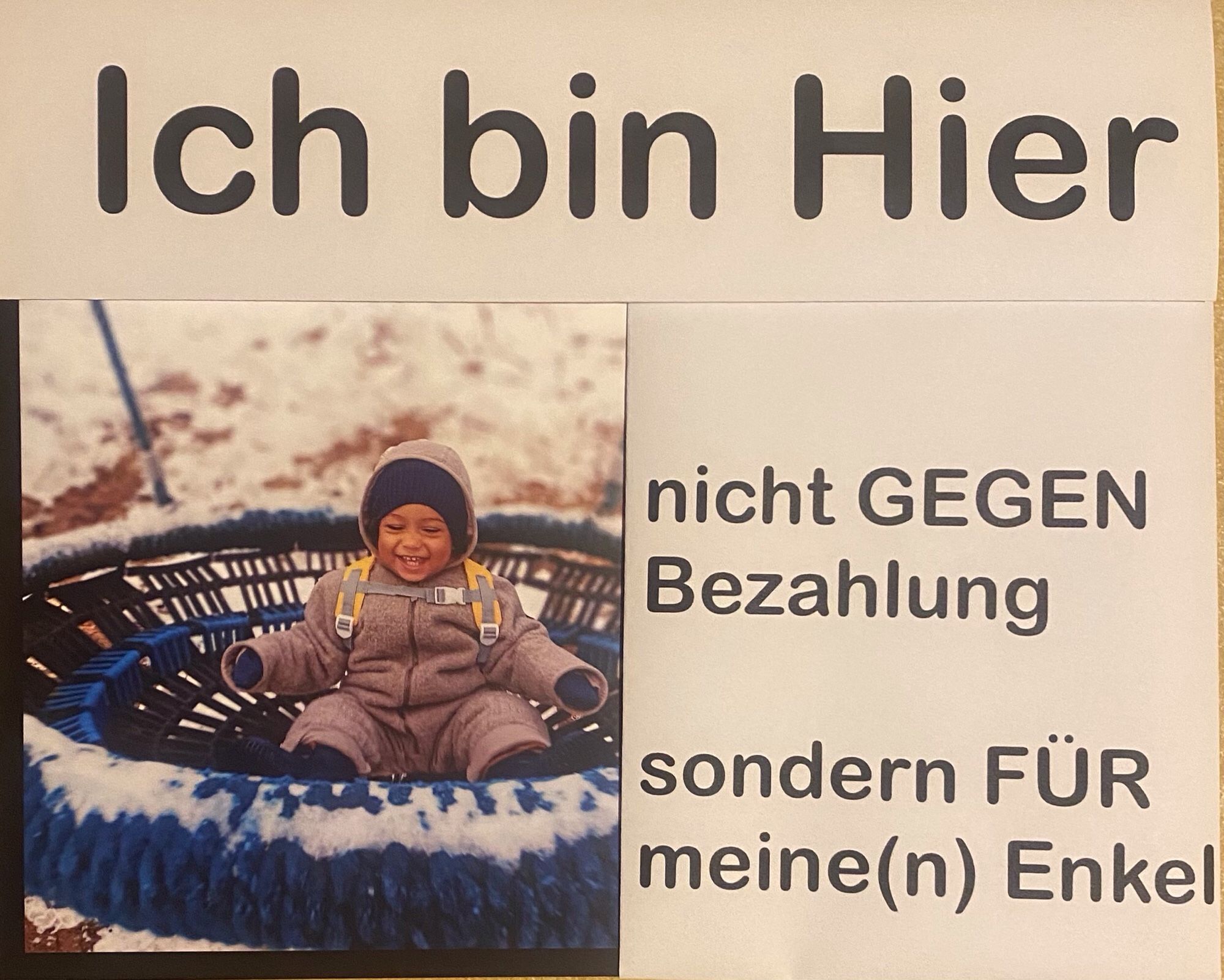 Plakat mit einem Foto meines Enkels afrikanisch-europäischer Abstammung und dem Text: „ich bin hier, nicht gegen Bezahlung sondern für meine Enkel“