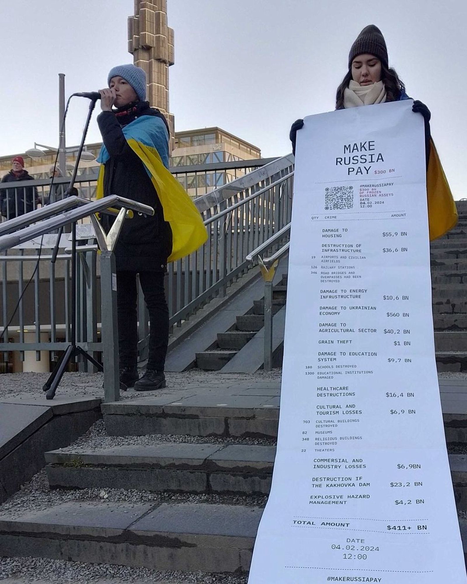 Manifestation en faveur de l’Ukraine à Stockholm en Suède dimanche 4 février (hier).
Pendant qu’une manifestante couverte d’un drapeau ukrainien (jaune et bleu) est au micro, une autre présente un gigantesque ticket de caisse où est marqué « Make Russia Pay » et une liste de destructions (avec le coût) et un total au 4 février 2024 de 411 milliards de dollars: