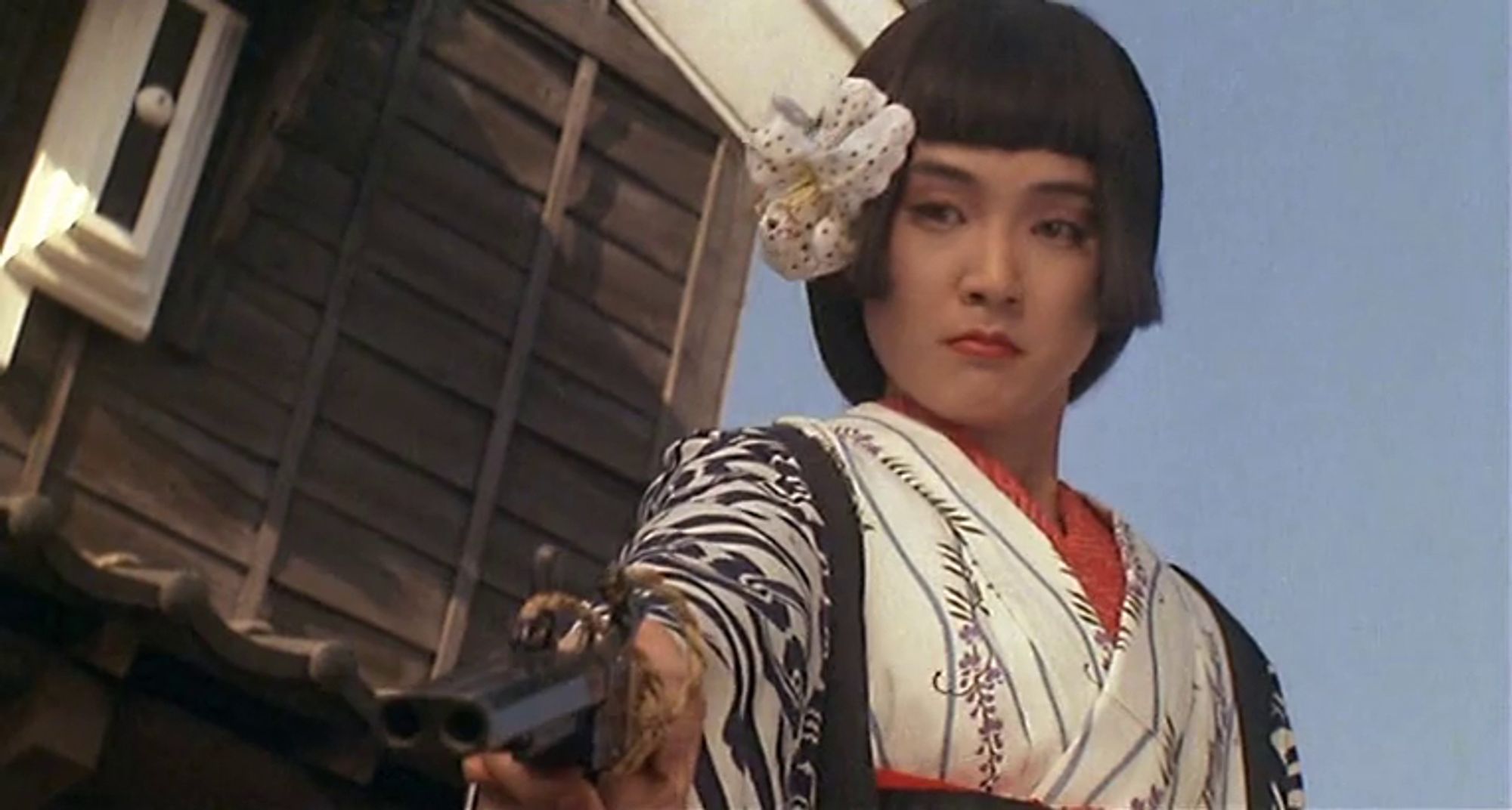 Narumi Yasuda as Yuri the Pistol. She is pointing a gun downwards to a character offscreen