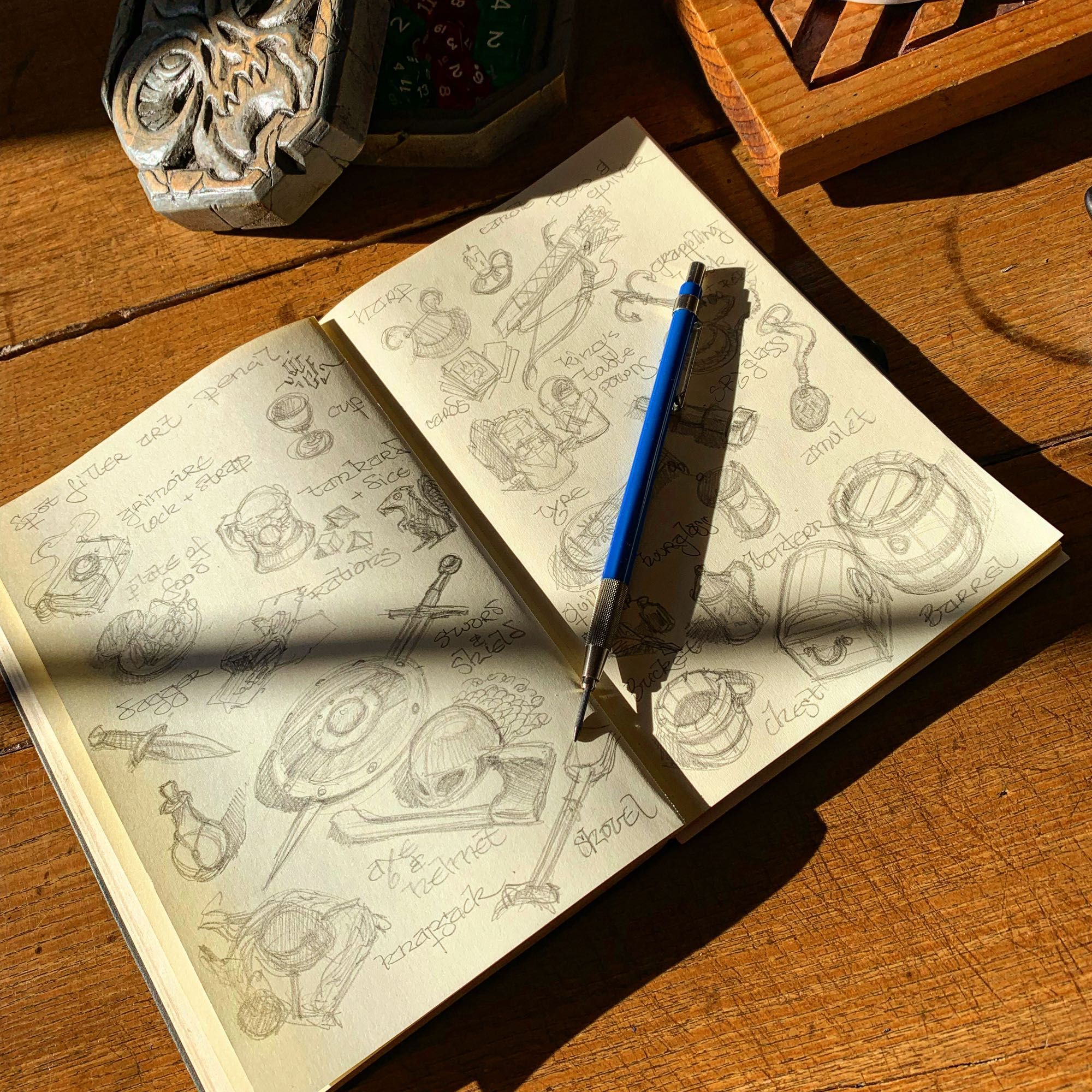 My current sketchbook with the late afternoon sun shining on it. On a double page spread, I have doodles a whole list of high adventure items.