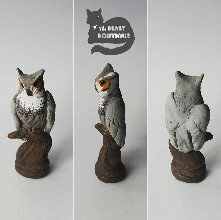 A figurine of a Great Horned Owl perched on top of a small twisted stump.