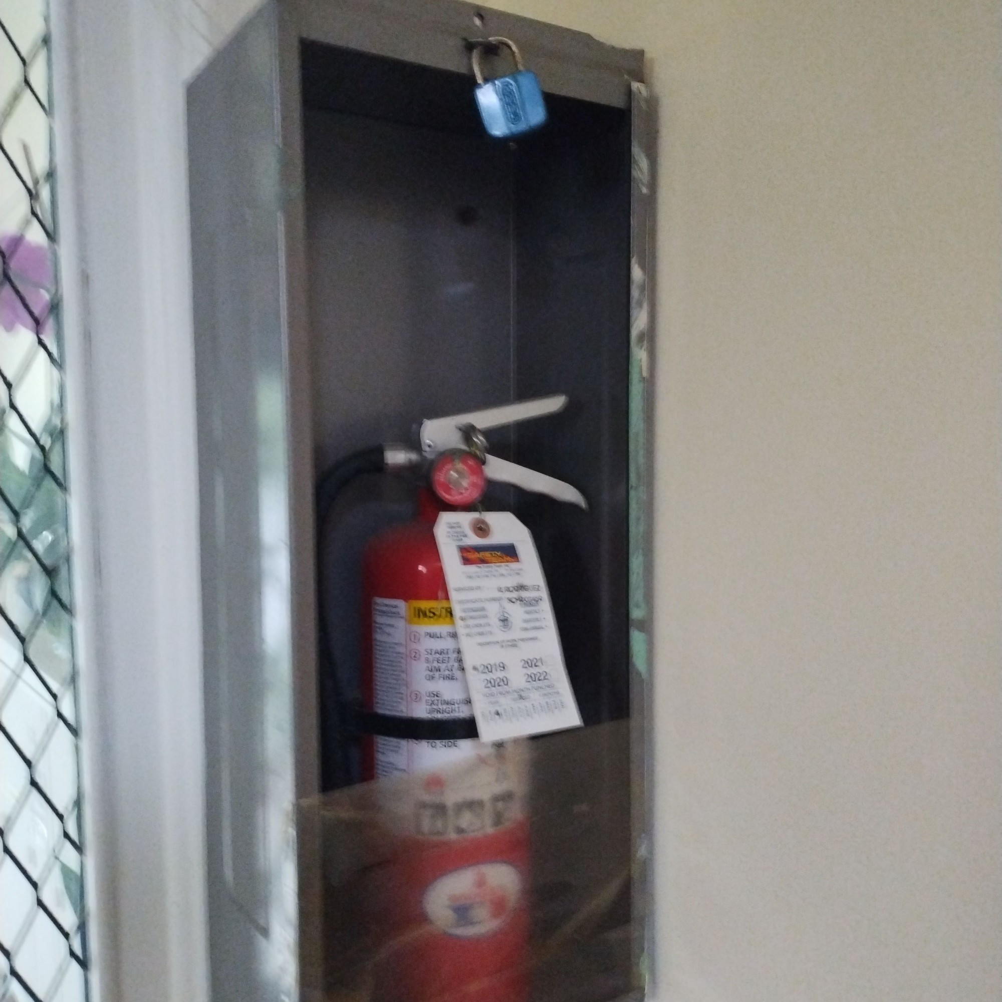 Fire extinguisher in a case for which the glass has already been busted open (but is still locked)