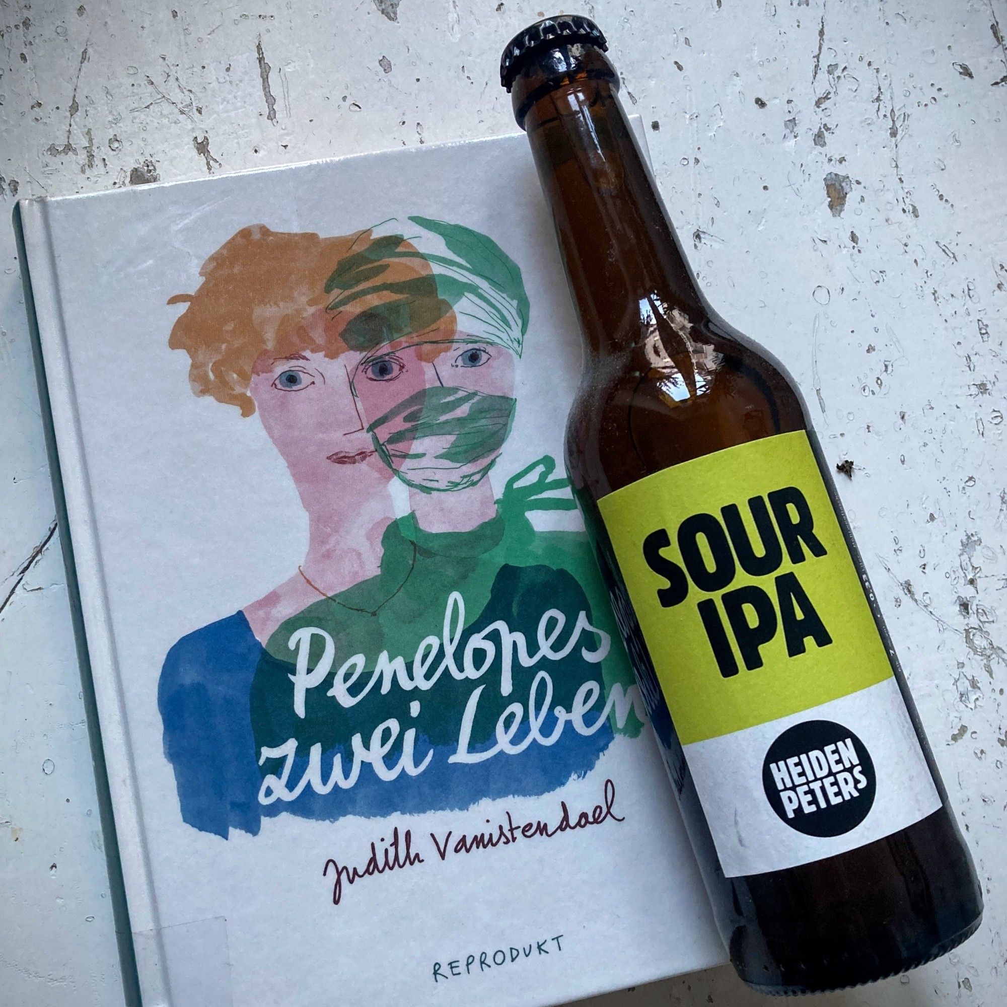 Eine Flasche „Sour IPA“ von Heidenpeters. Darunter der Comic „Penelopes zwei Leben“ von Judith Vanistendael, erschienen bei Reprodukt.