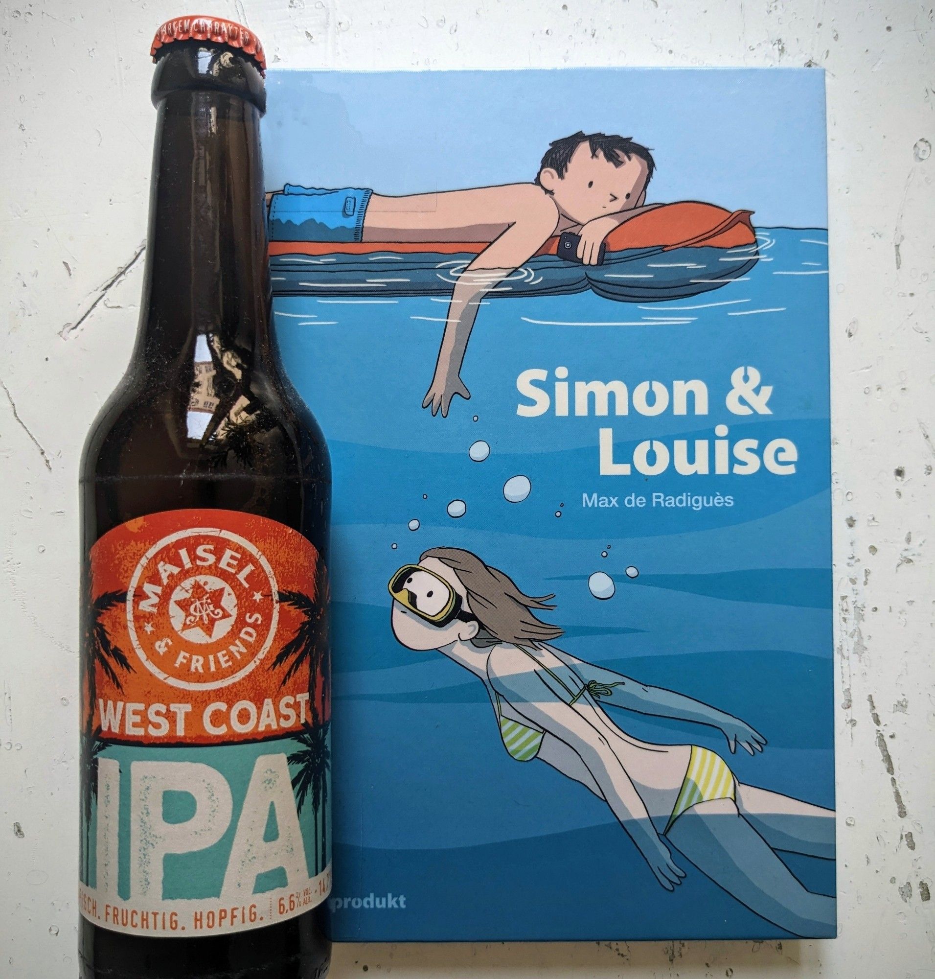 Flasche West Coast IPA von Maisel & Friends auf dem Cover des Comics „Simon & Luise“ von Max de Radègues auf dem beide Charaktere abgebildet sind: Er auf einer Luftmatratze liegend, sie darunter tauchend.