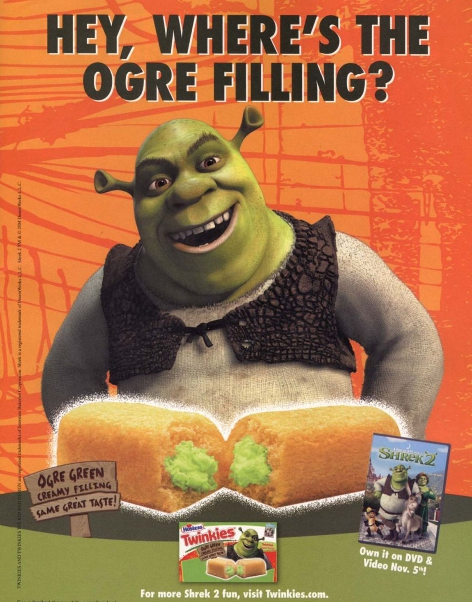 Shrek laughs with his hands on his hips in front of an abstract orange background. A yellow spongecake is split in half in front of him, revealing green creme. In the bottom corner is a picture of the DVD cover for Shrek 2