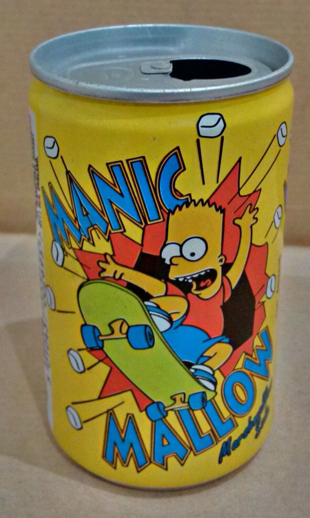 Bart Simpson crashes through the wall on a skateboard, on a yellow pop can. He is surrounded by the words Manic Mallow, as marshmallows fly about in various directions