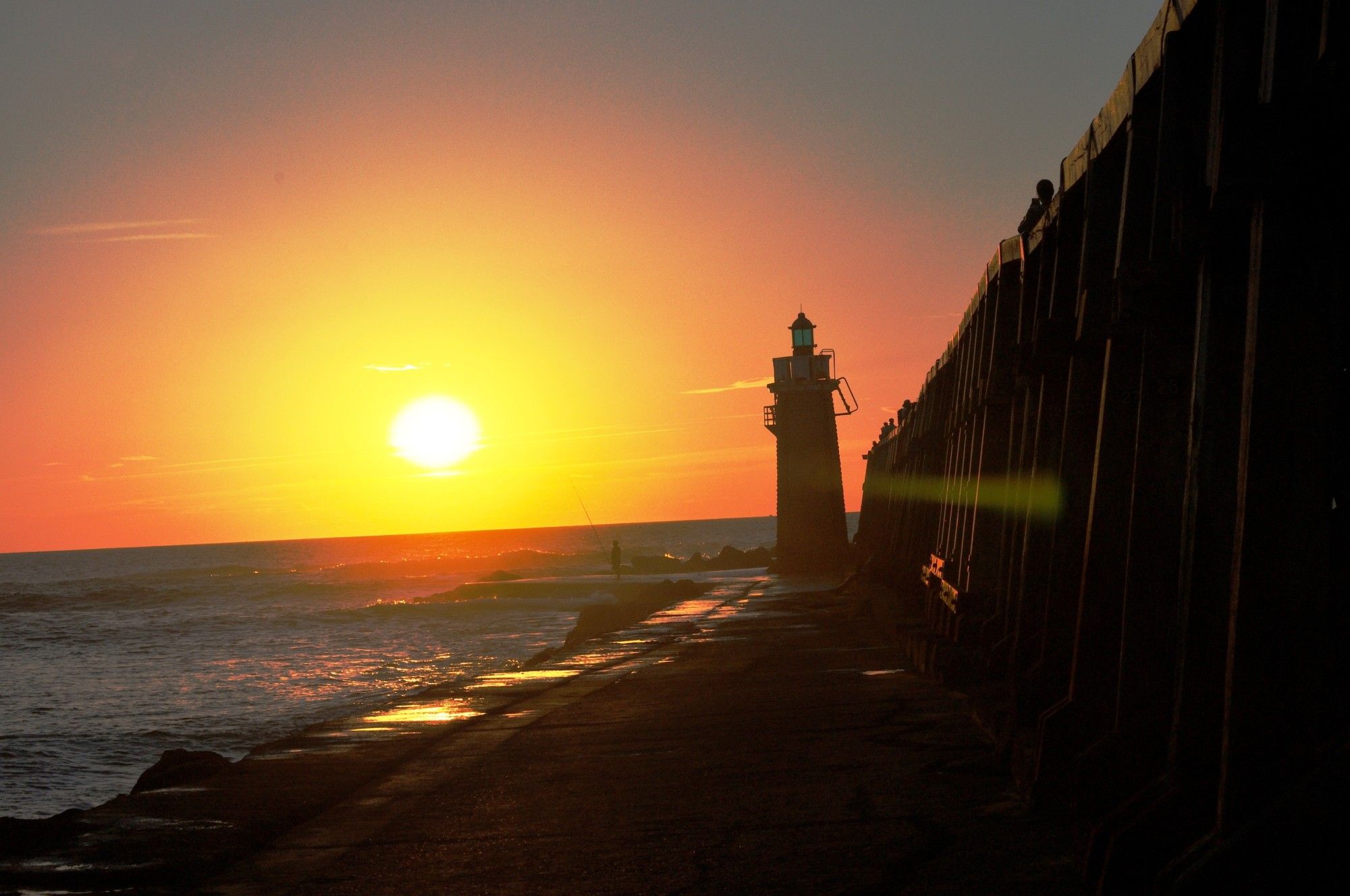 le soleil se couche sur l'océan avec le phare et estacade de Capbreton