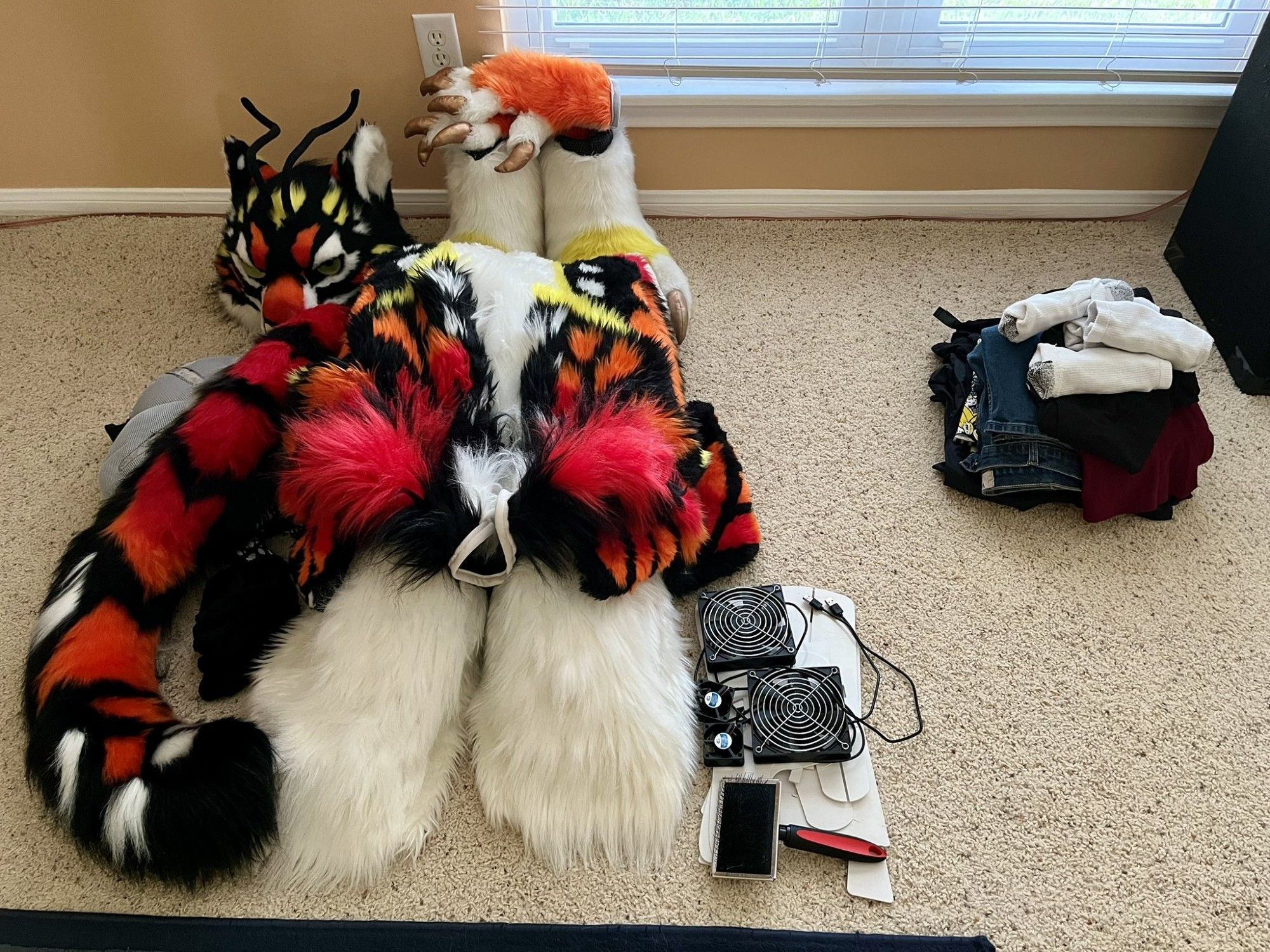 Fursuit and accessories next to a small pile of clothes to be packed for a long-weekend trip