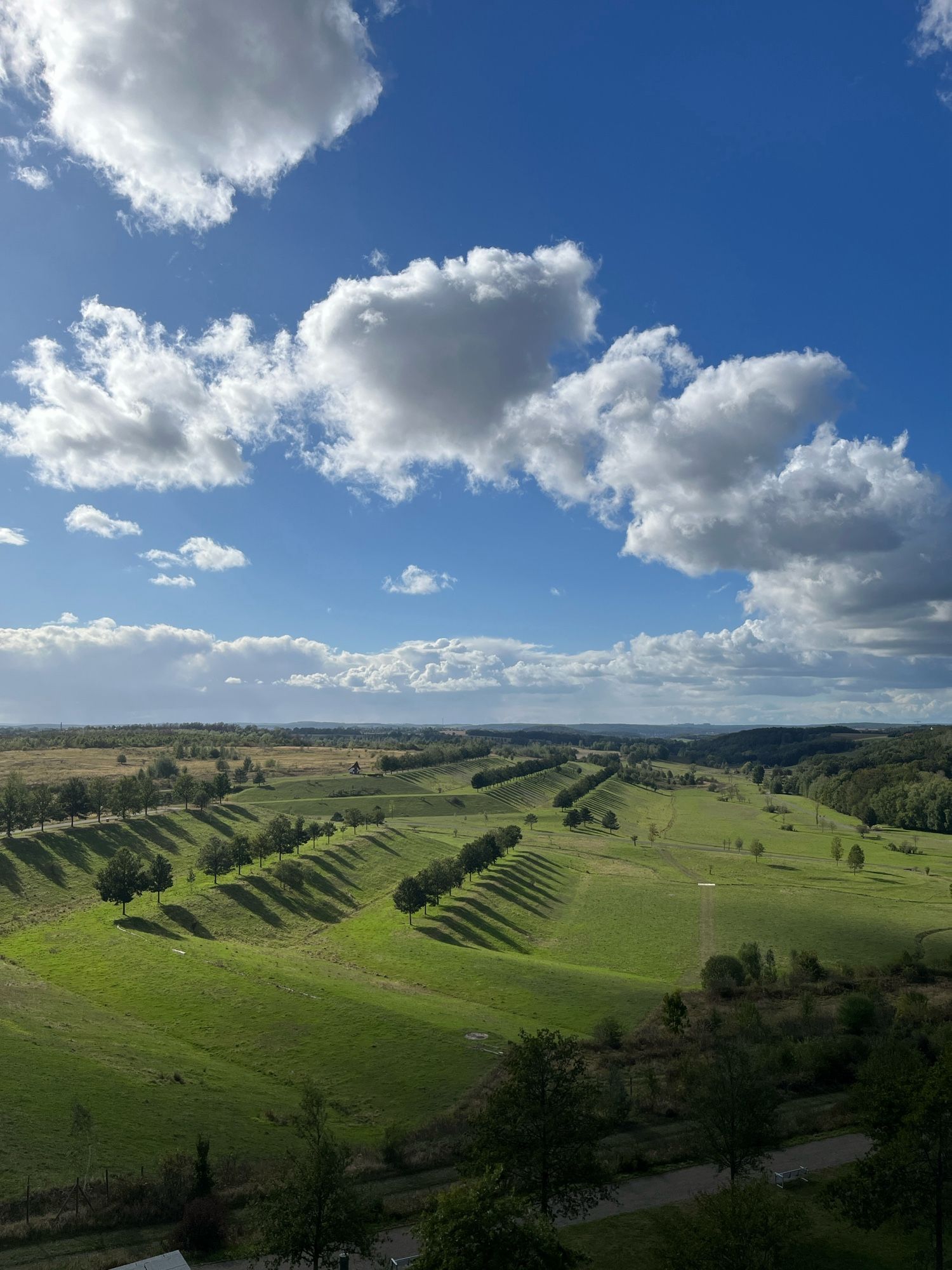 A former uranium mine turned into a park. Green hills below a blue sky and white clouds on the top.