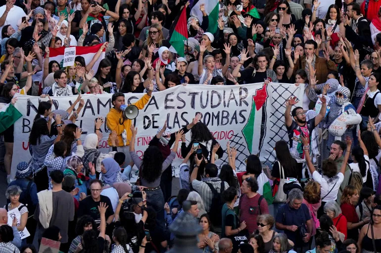 Scores of people gather in assembly to raise their hands against the continuing genocide in Gaza, specifically for an immediate ceasefire, to free Palestine and halt weapons trade. Faces blurred, swathes of color flashing and reaching— it’s alive and resonant. One can feel the collective energy of a resonating chant, ongoing. Free free free Palestine!