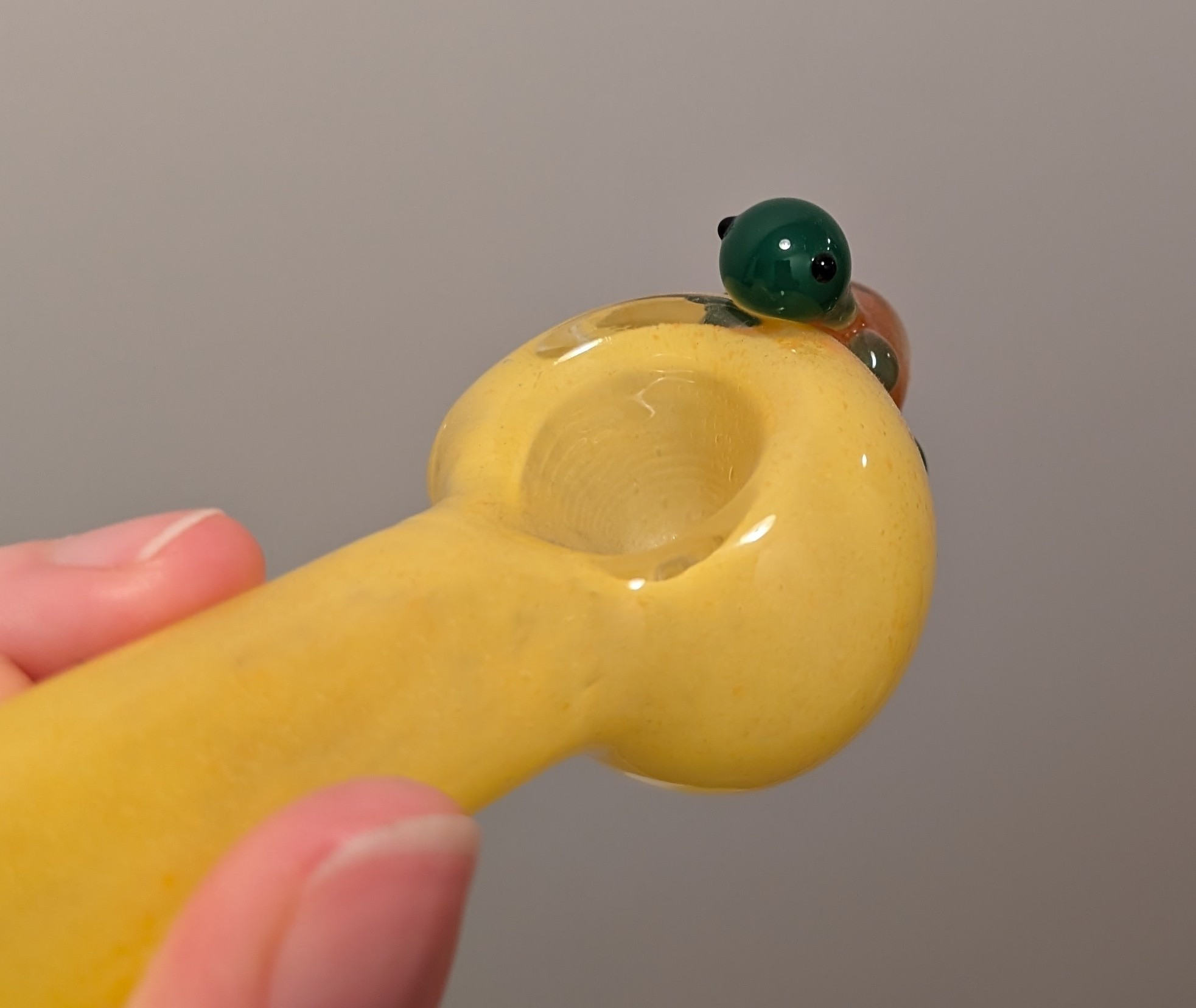 cute little glass turtle peeking over the edge of the weed pipe's bowl