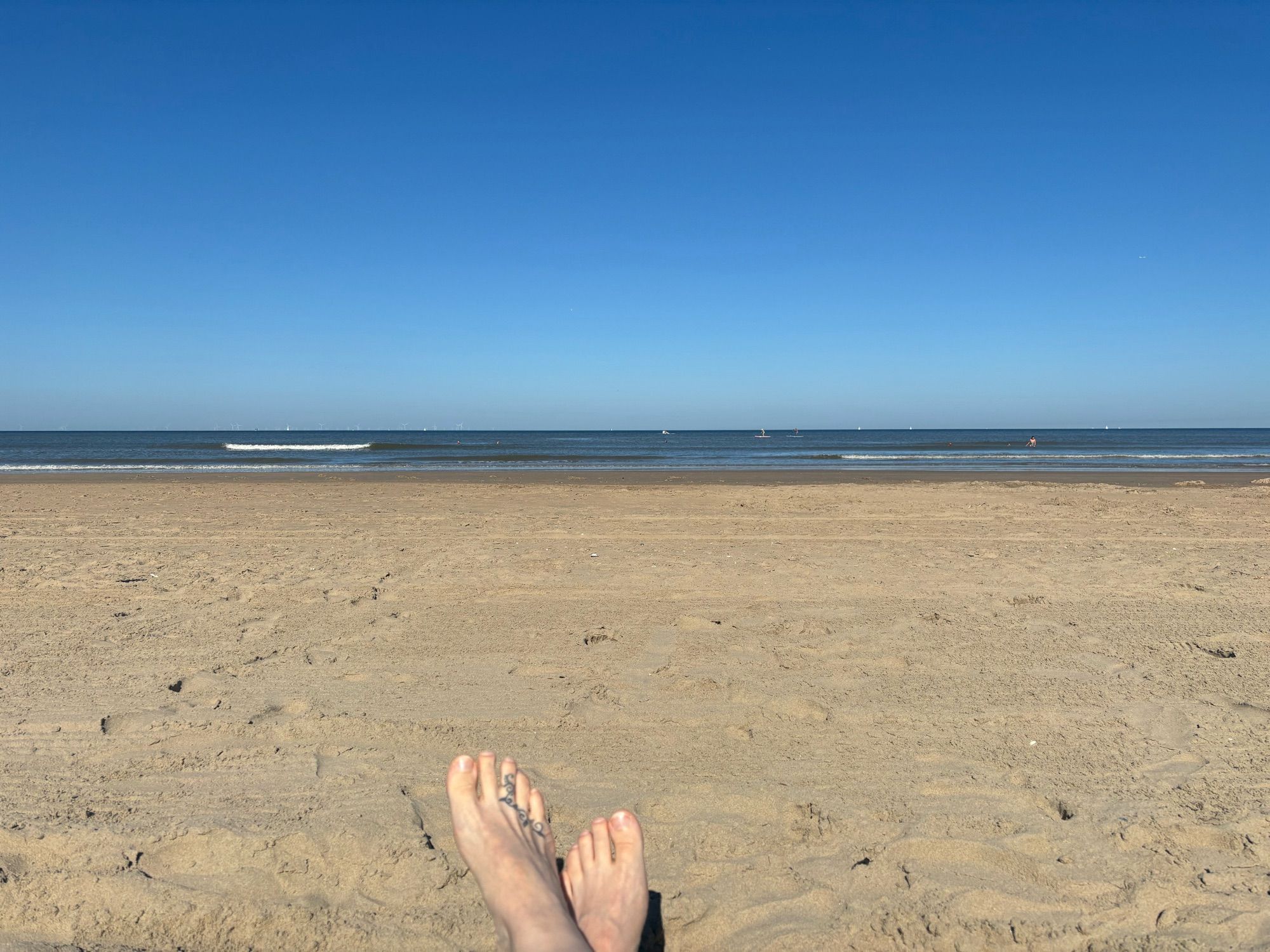 Bild vom Strand mit Füßen am unteren Rand. 
Man bemerke die GERADE Horizontlinie! ☝️😂