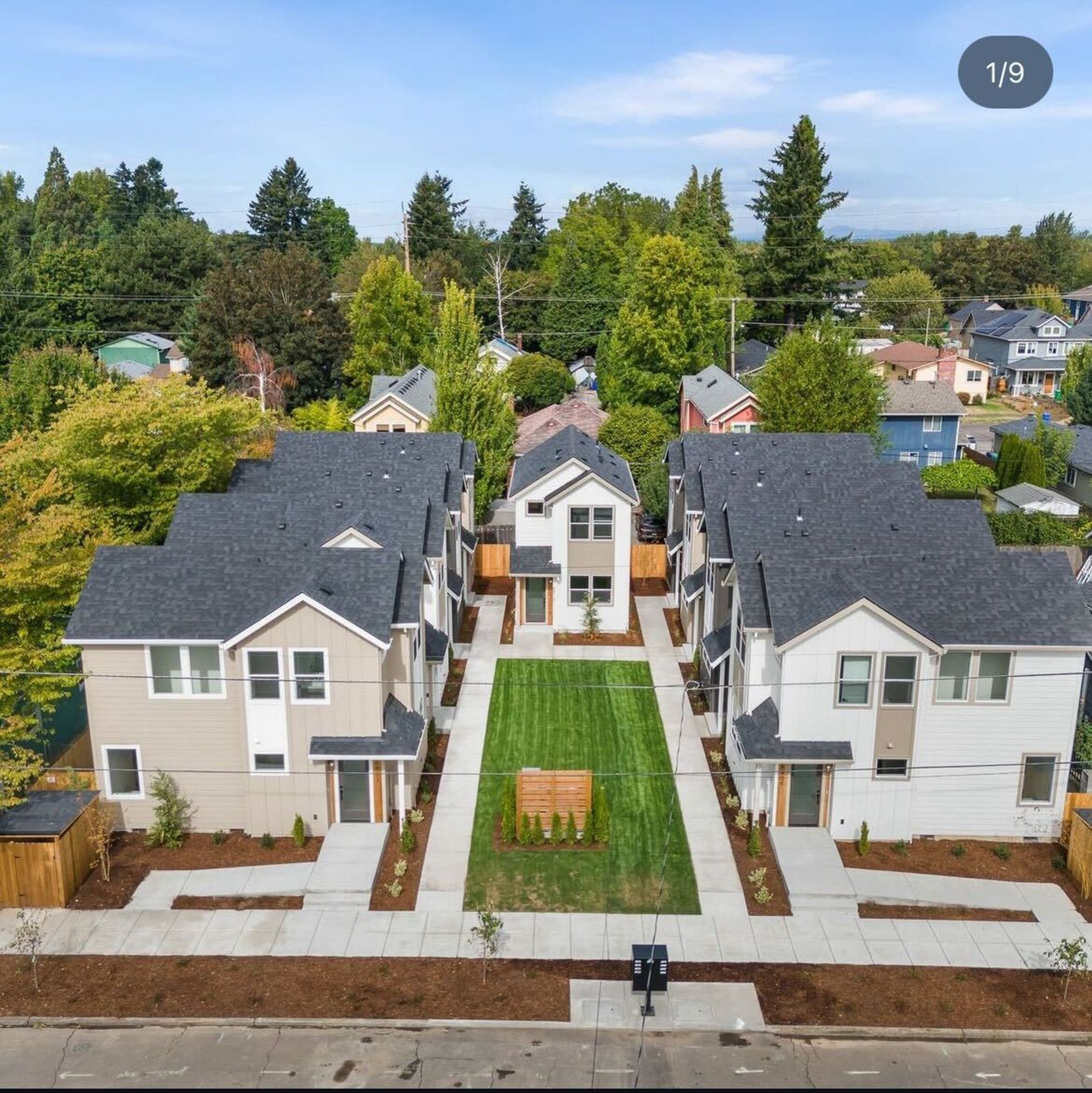 Aerial view of the 9 new homes; 4 on each side of the common green space and one at the end. Project included construction of a new sidewalk, where there was no sidewalk previously. The front two units have an accessible ramp from the sidewalk to the front door.