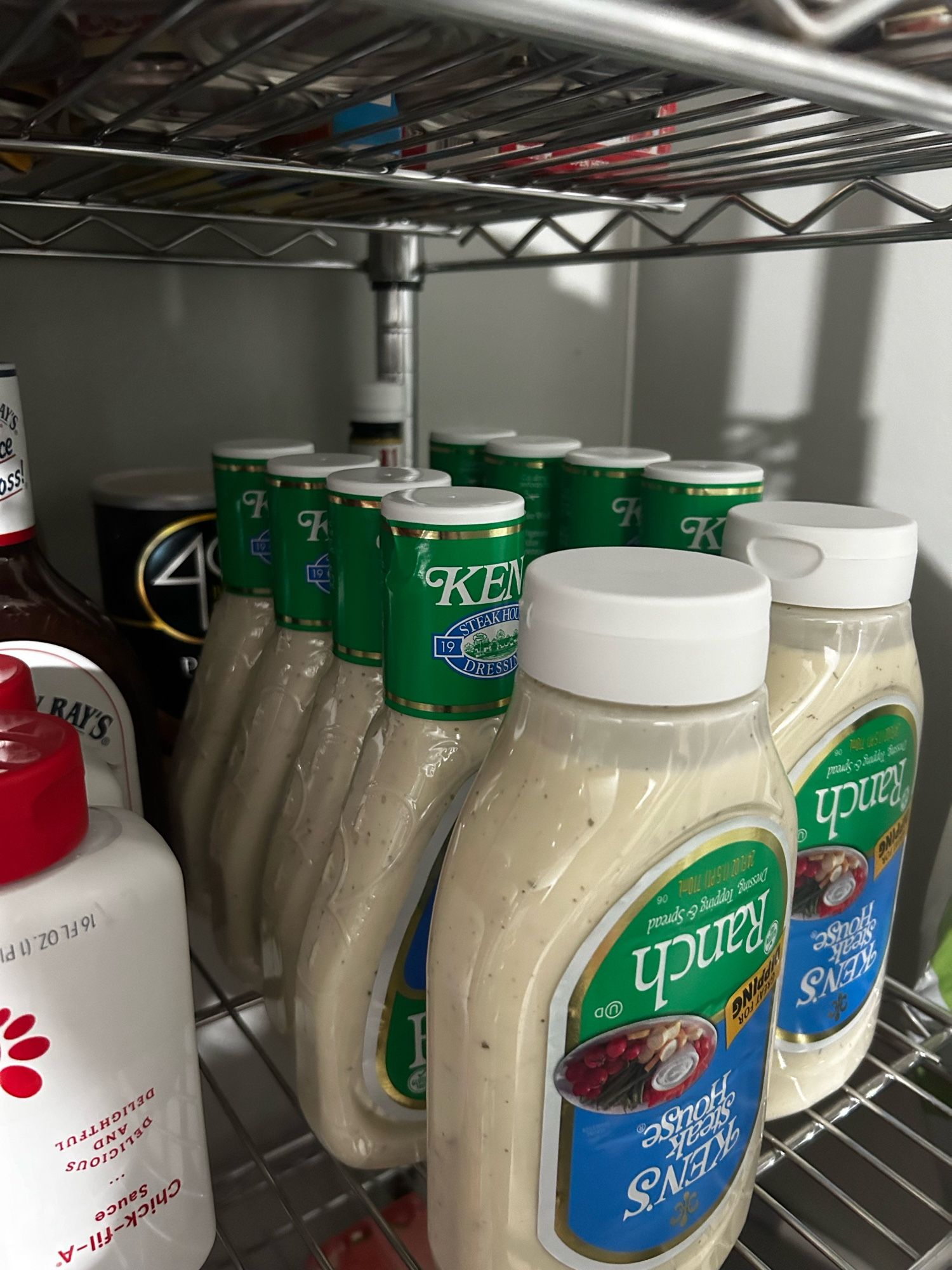 Metal pantry shelf with bottles of sauces, 10 of them are ranch.