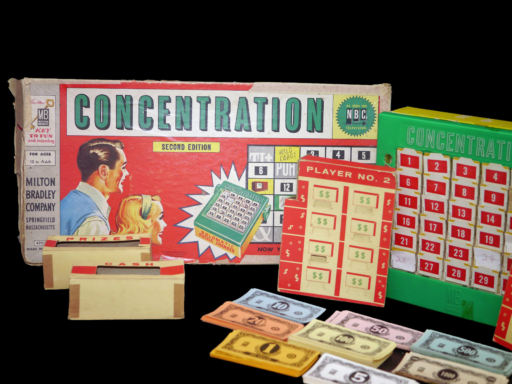 the board game of Concentration showing a green rebus board and a bunch of cash and a player board and some prize envelopes for some reason