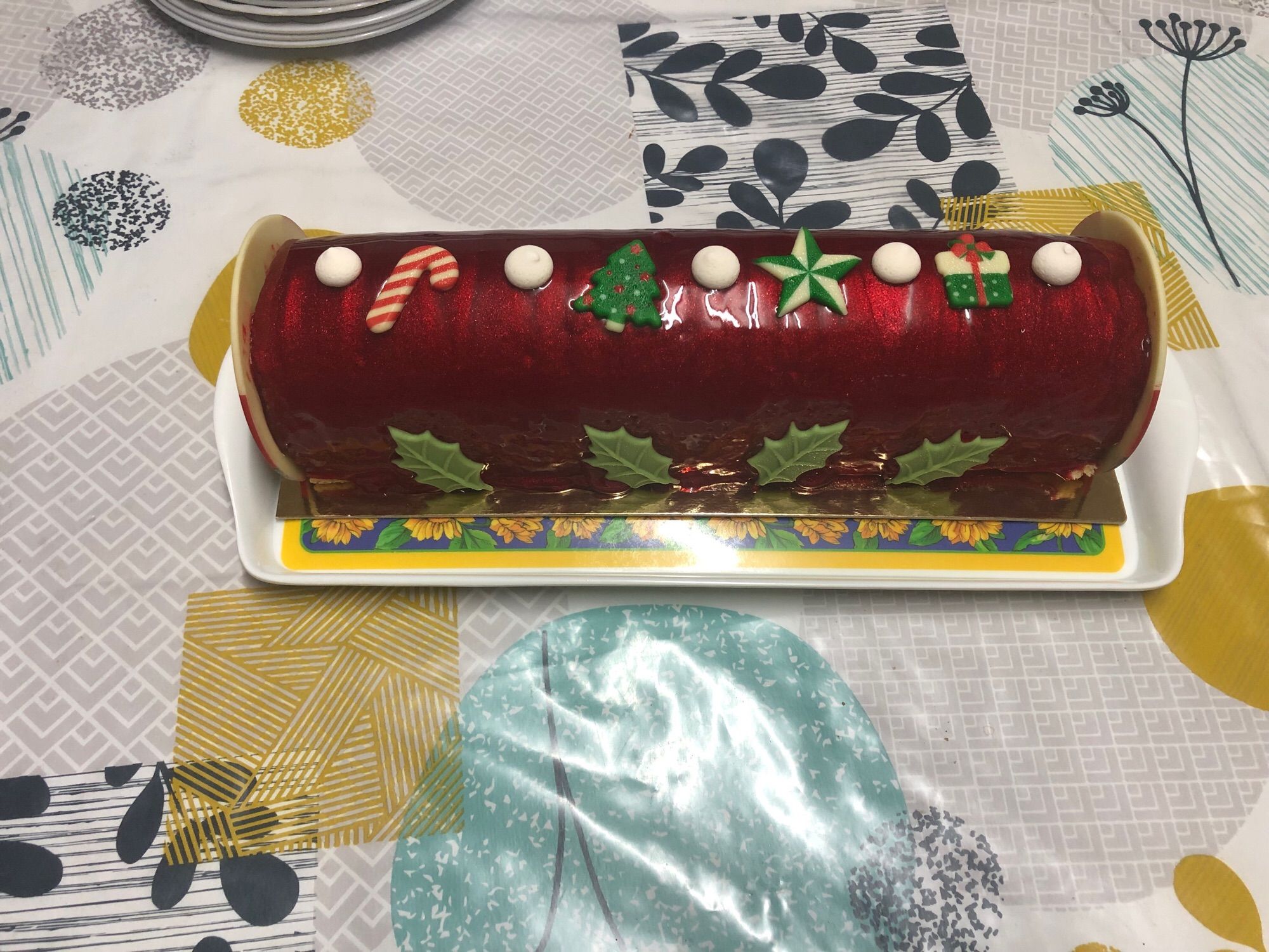 Buche rouge à paillettes décorée de petites meringues, et sucre d’orge, sapin, étoile et cadeau en chocolat colorés