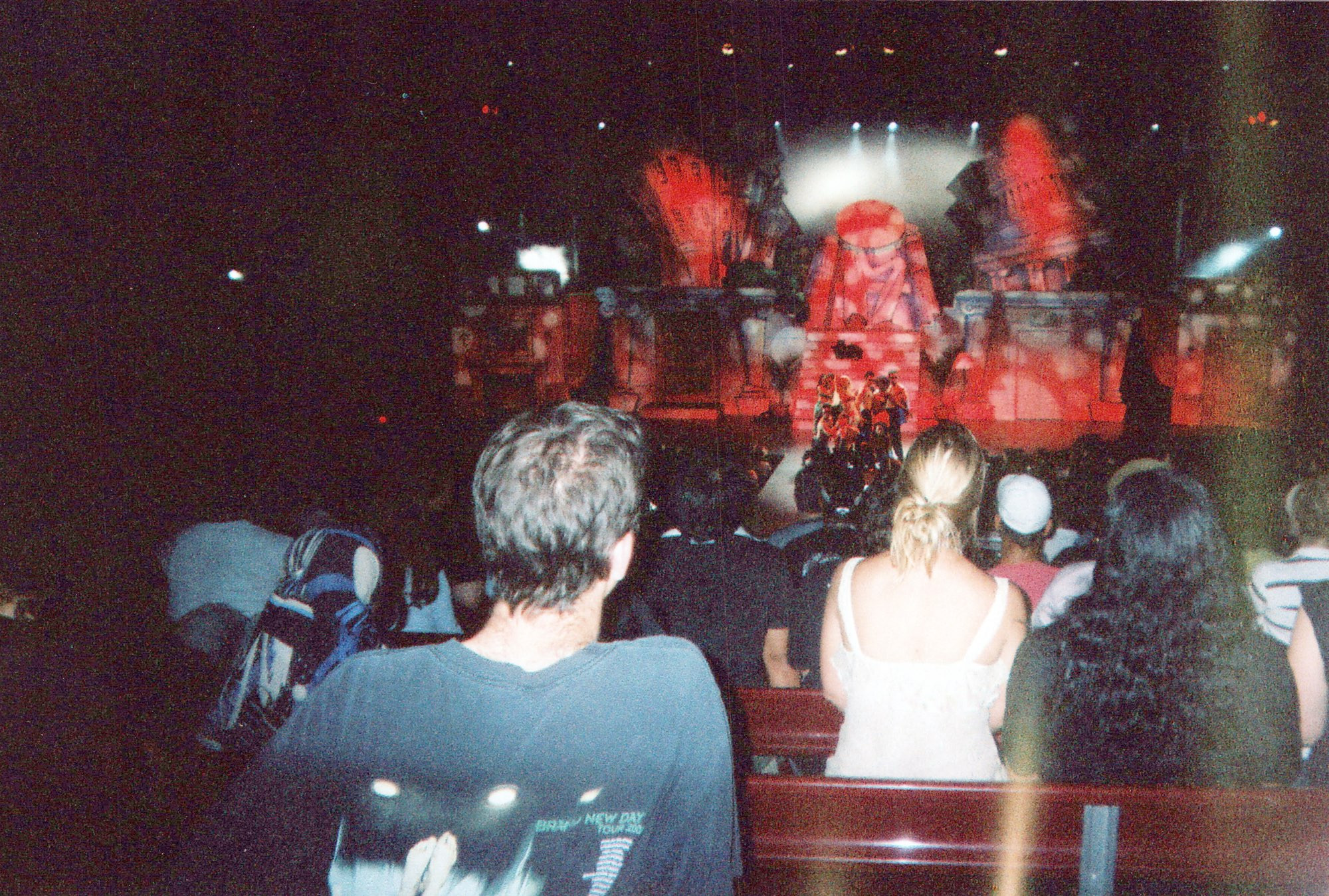 The opening dance of Bill and Ted. In the foreground, the crowd watches the stage. On stage, a clump of dancers dance in from of a flood, hand-drawn version of the Lincoln memorial. An oval hides the statue’s face. 