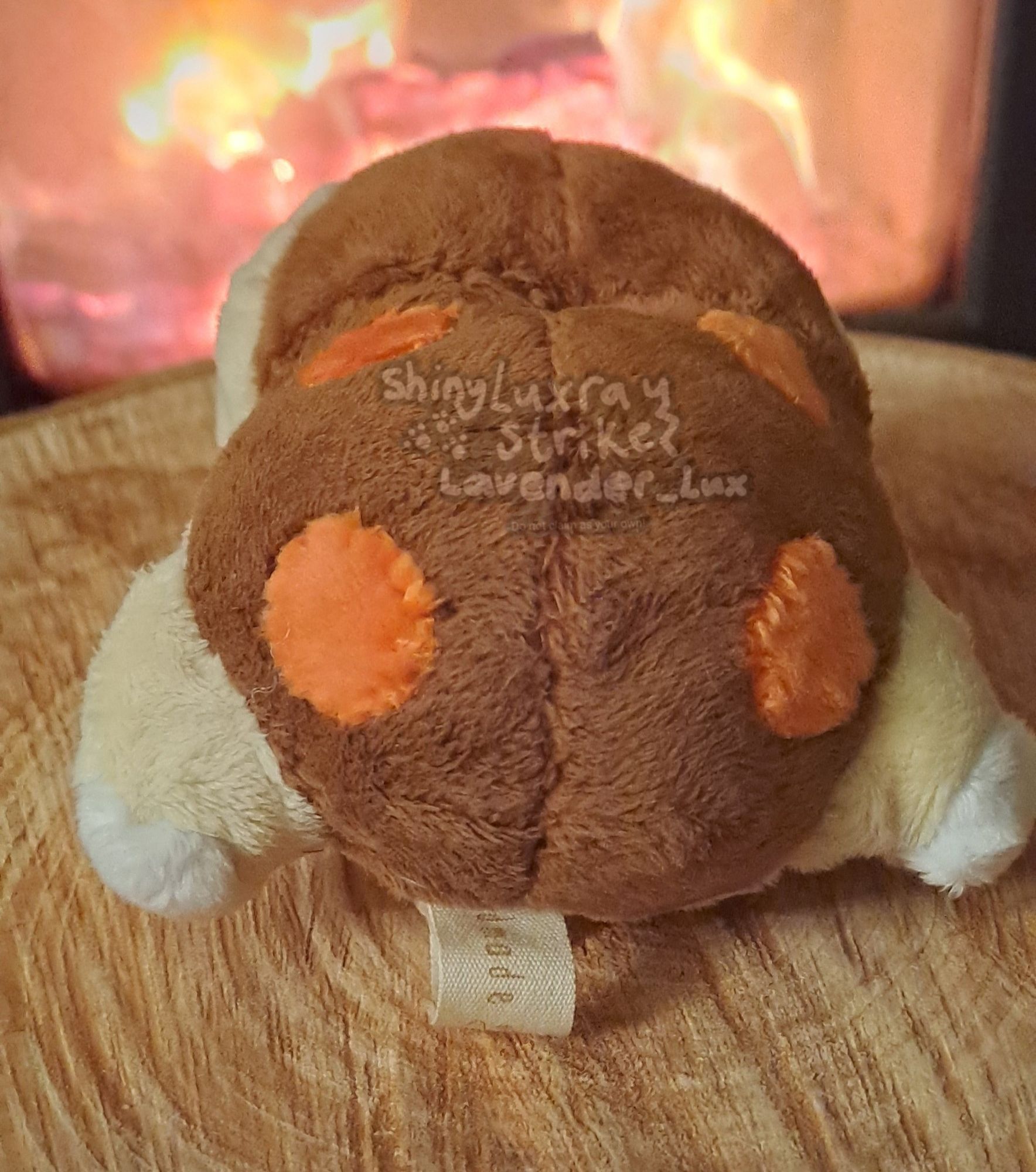 Custom plush of shiny Cyndaquil. Pattern is from a bootleg Cyndaquil pokedoll I seam ripped. 

Cyndaquil, a tan colored pokemon with closed eyes and a brown back with 4 red dots, lies on a piece of wood in front of a fireplace