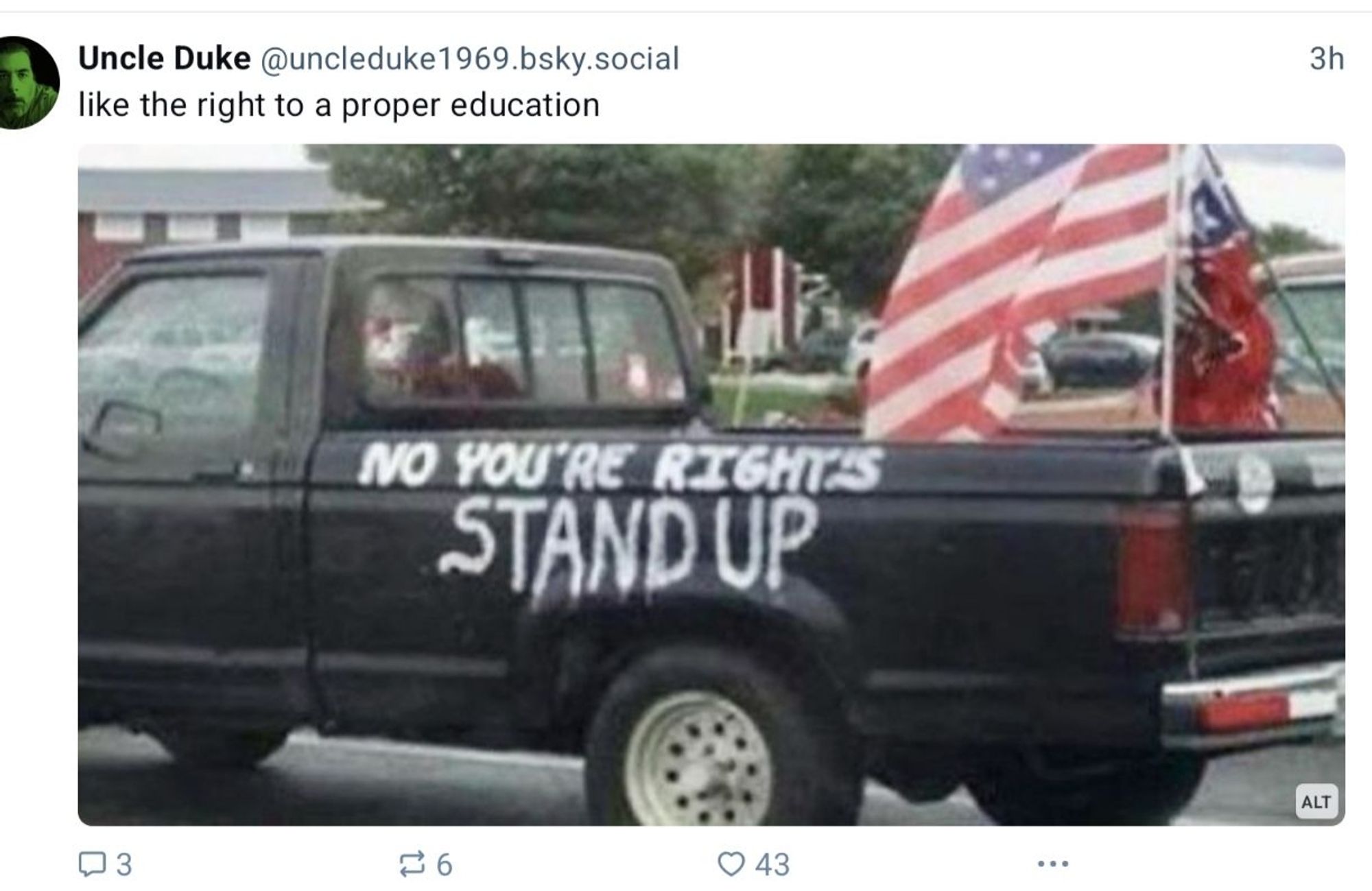 Black pickup truck flying American flag, spray painted on the side: NO YOU'RE RIGHTS/ STAND UP