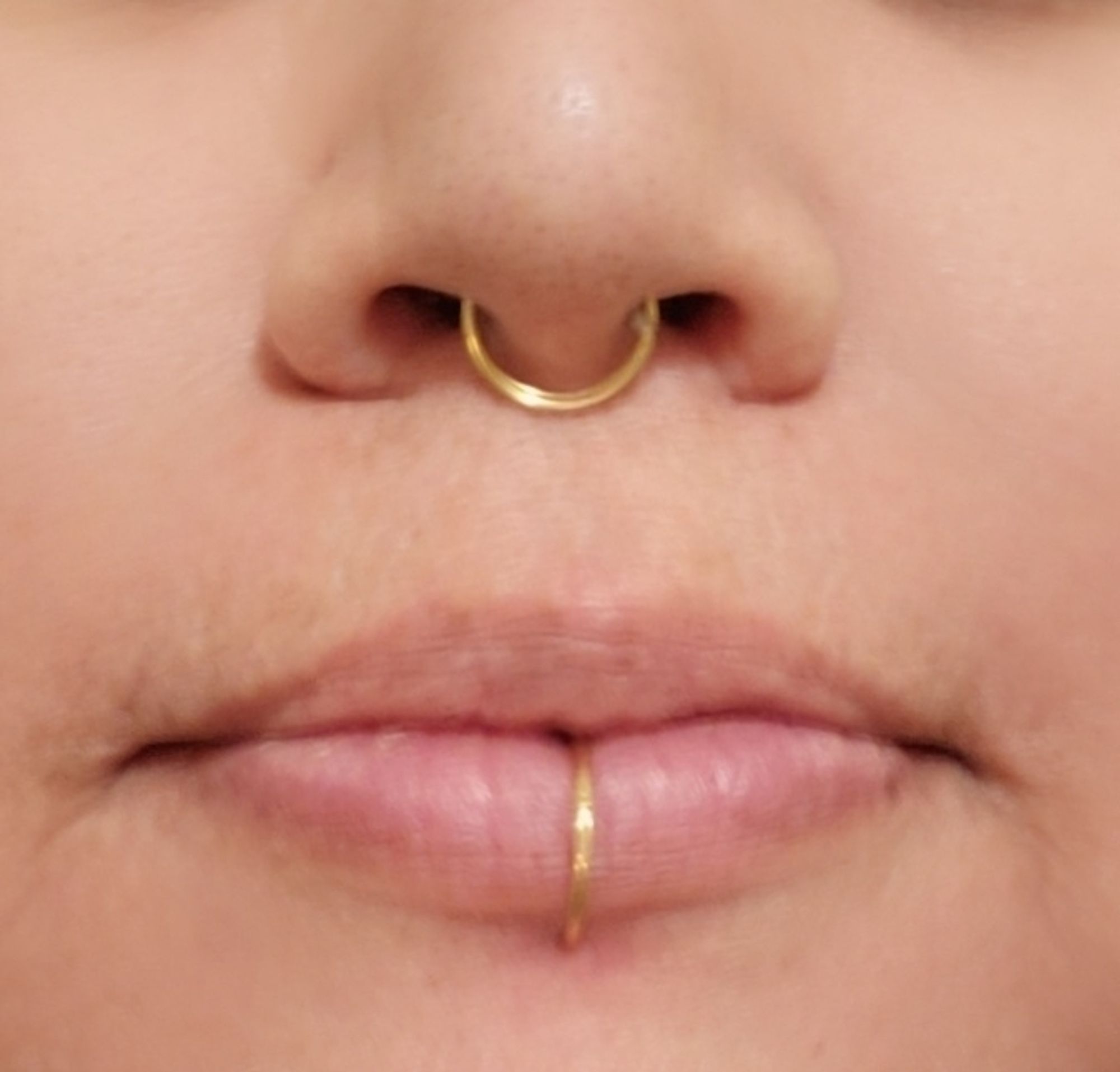 A close up of a person's lips and nose with gold hoops