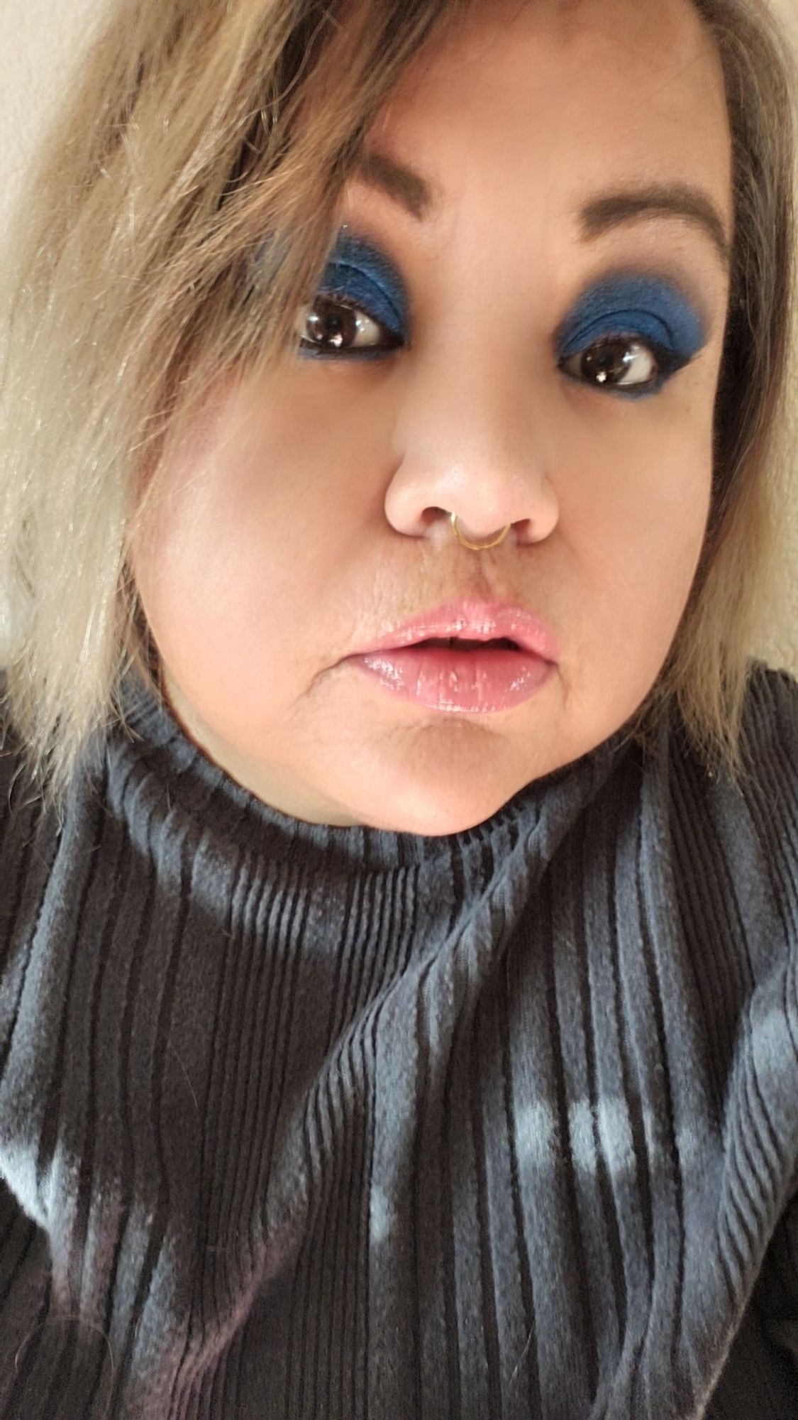 Middle aged Mexican filipino woman with a bob. Sbes wearing a gray sweater and blue eyeshadow