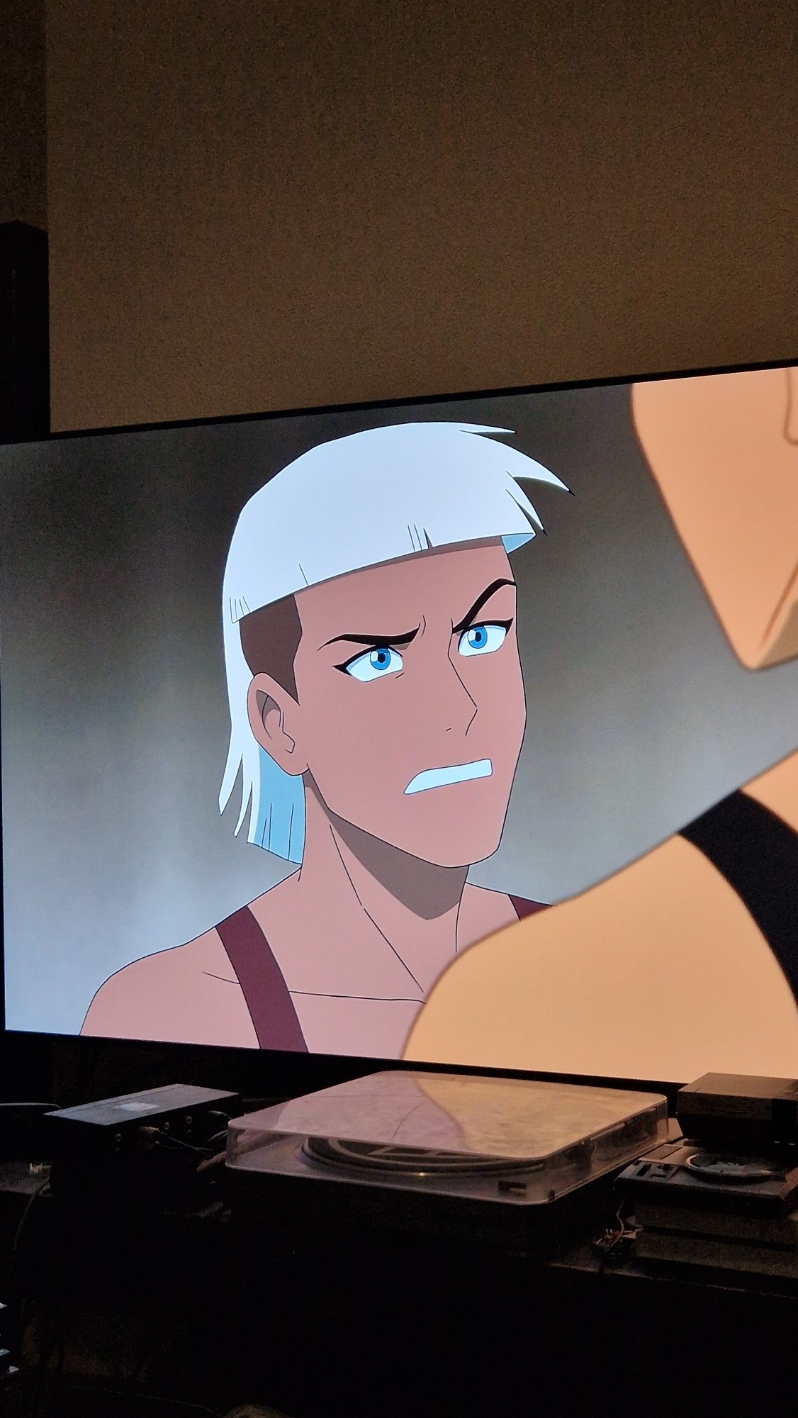 Cartoon character closeup: a brown-skinned woman with white short hair and an undercut. She's wearing a tanktop.