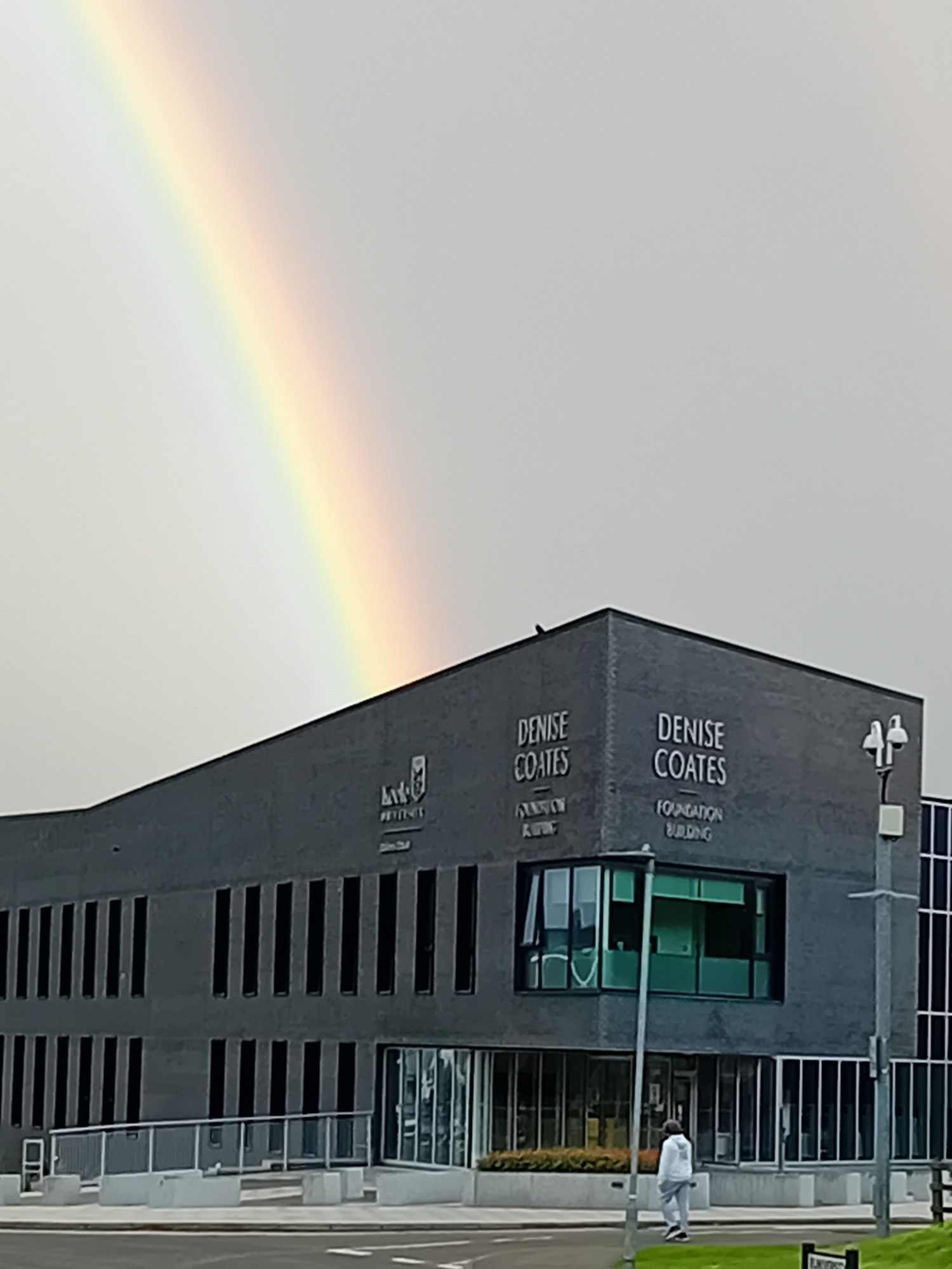 A big wide rainbow ending at a business school building