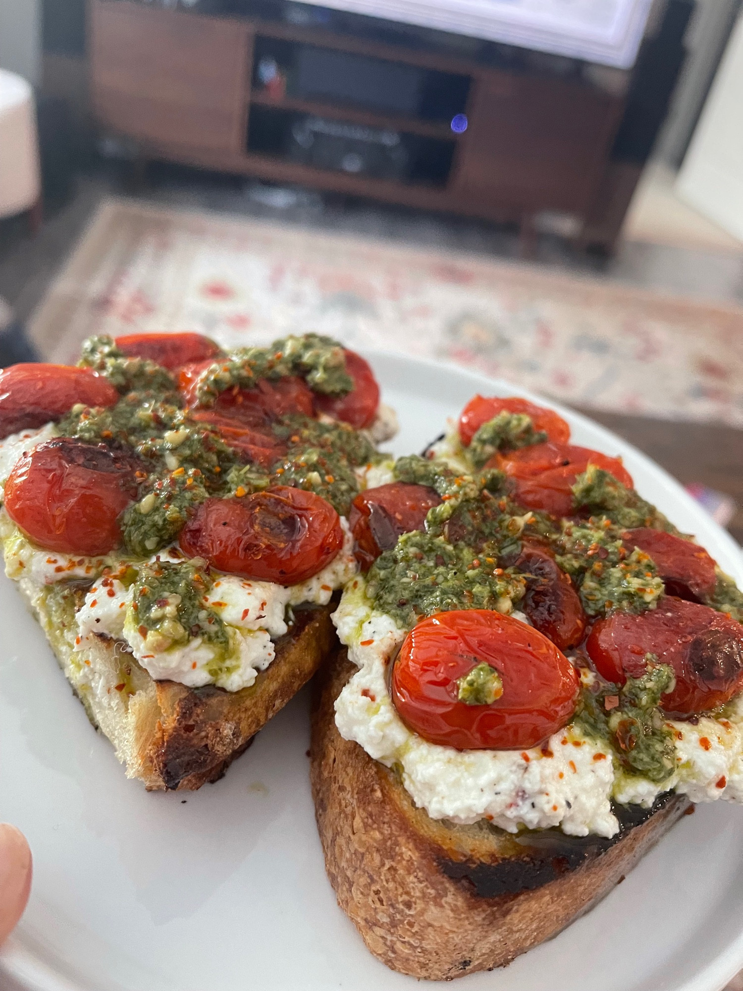 some sourdough toast with some ricotta spread that i mixed with some grated garlic and some grated parmesan and some black/red pepper that i then topped with some sauteed grape tomatoes and some pesto and some aleppo pepper