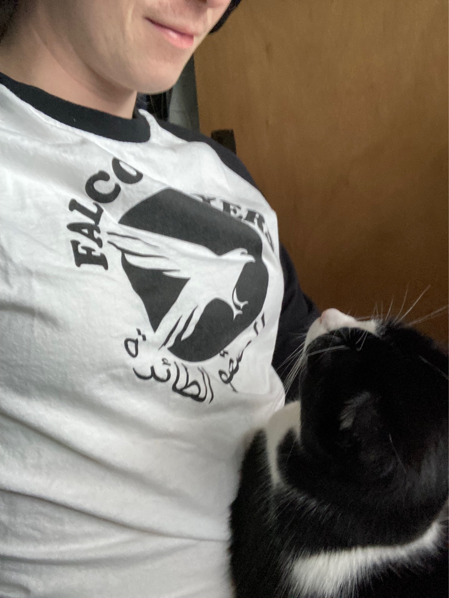 A picture of me with my cat, Domino, in my lap. I am wearing a shirt for the Falcon Flyers, the Dubai Junior League Hockey Champions in 2001. Domino is looking at me lovingly.