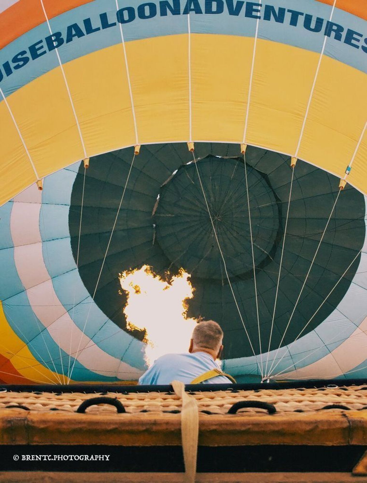 Photo of a hot air balloon being inflated with the basket on its side and flame burningPhoto of a hot air balloon being inflated with the basket on its side and flame burning