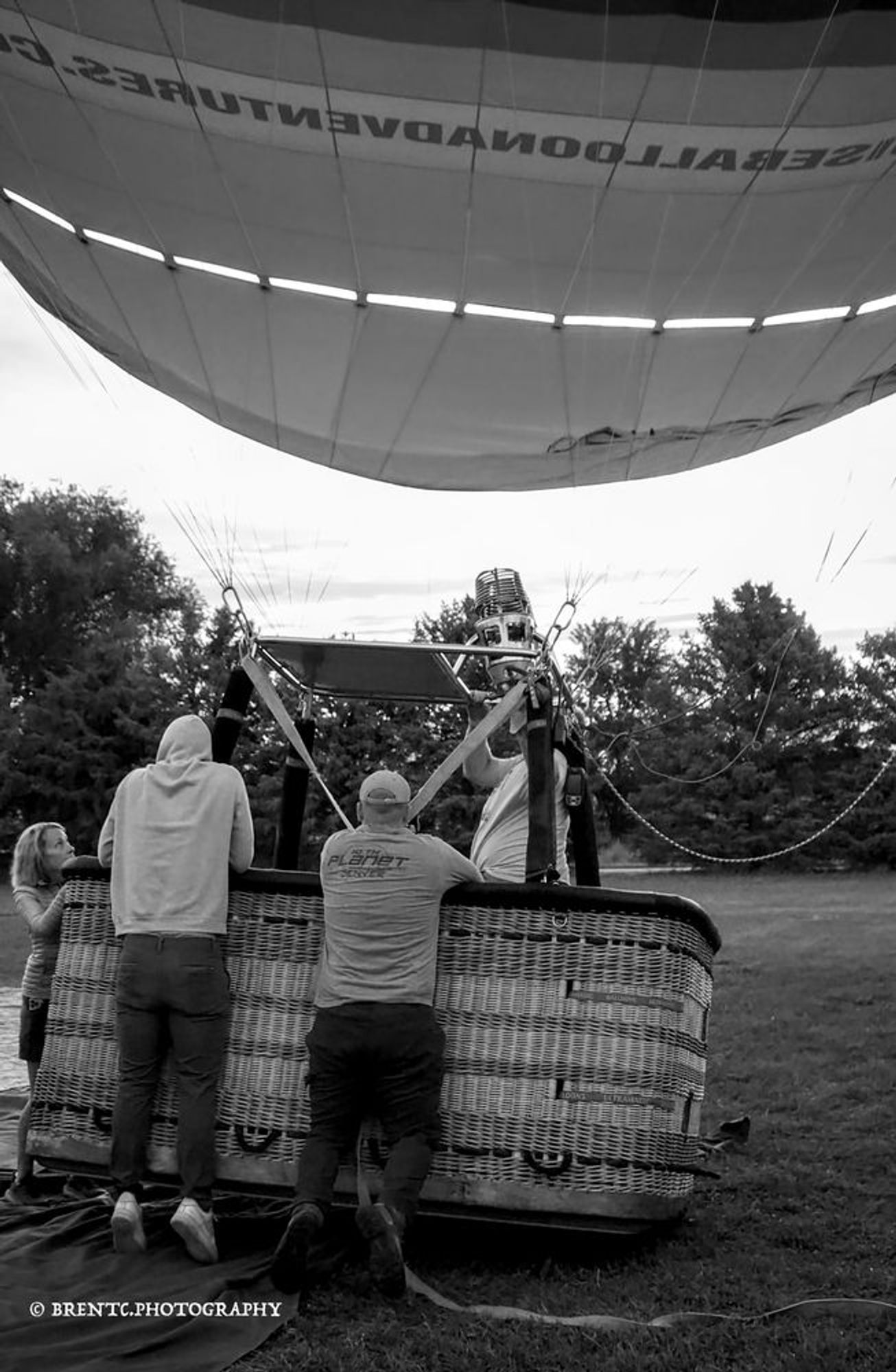 Black and white photo of two men weighing down the basket of a hot air balloon to allow passengers to climb inBlack and white photo of two men weighing down the basket of a hot air balloon to allow passengers to climb in