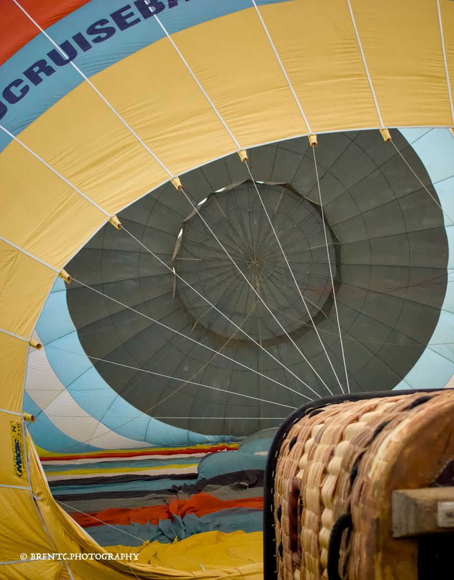 A hot air balloon on its side being inflated with part of the basket showing