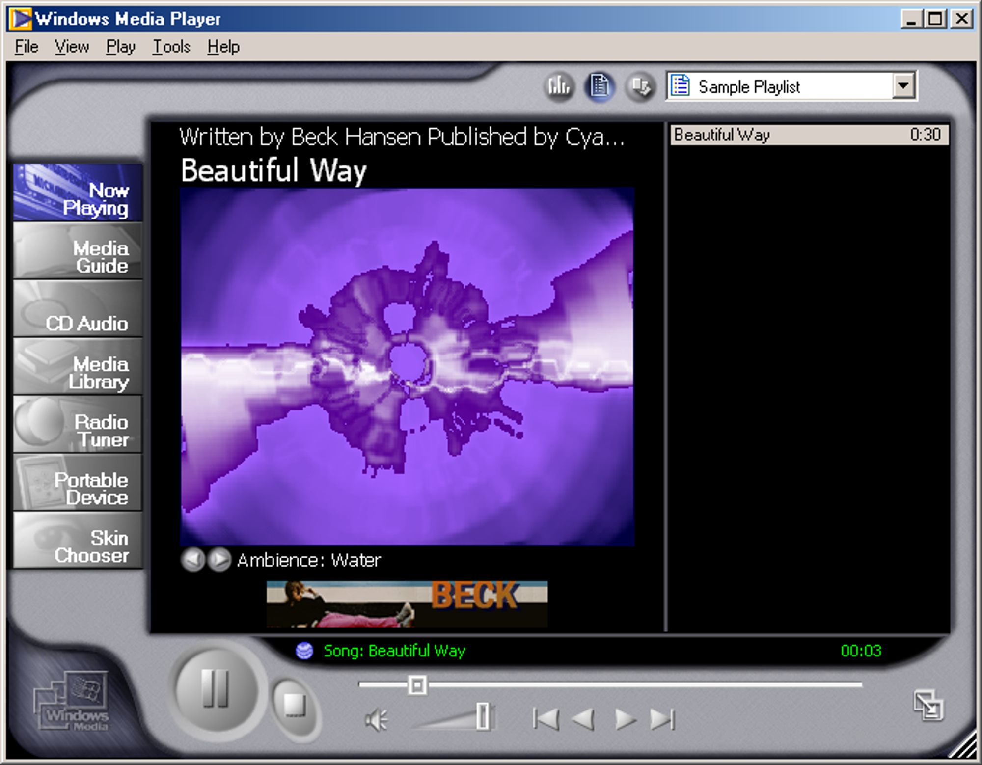 Print do Windows Media Player 7, em sua skin padrão, predominantemente com cores acinzentadas em sua moldura e preta em seu interior. À esquerda, um menu com vários botões, no centro, uma visualização "psicodélica" em tons de roxo, à direita uma playlist e, abaixo, os botões do player (play, pause, volume etc.).